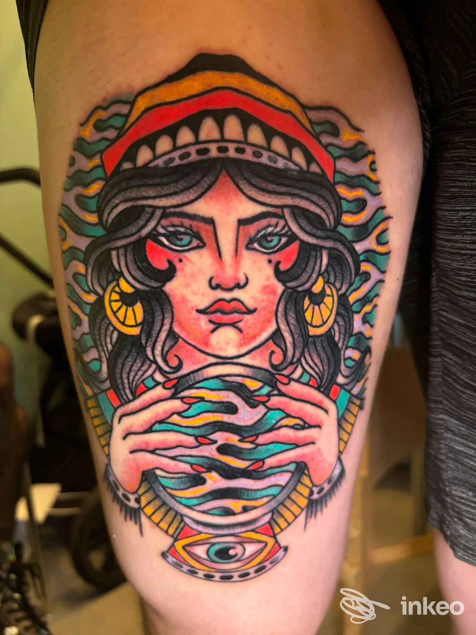 Tatuaggio colorato su coscia raffigurante una donna stilizzata con sfera e occhio decorativo, Tanuki Tattoo Studio, Ragusa.