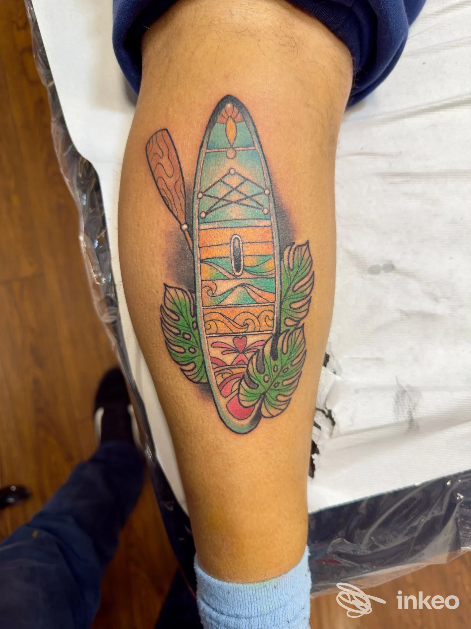 Tatuaggio colorato a forma di tavola/remo con foglie sul polpaccio, THE GOOD FELLAS TATTOO, Palermo.