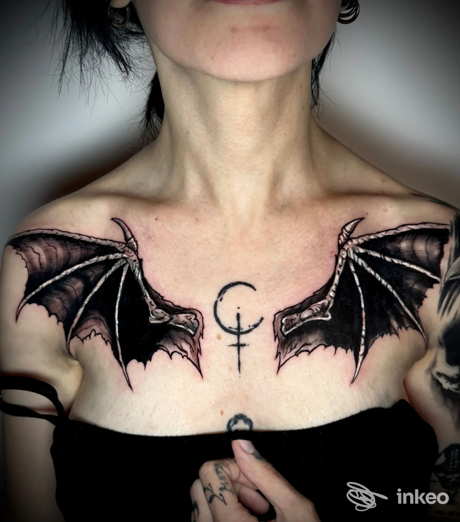 Tatuaggio a forma di ali scure sul petto con simbolo centrale, immagine fornita da Tattoo Club di Vito Scianna, Partinico.