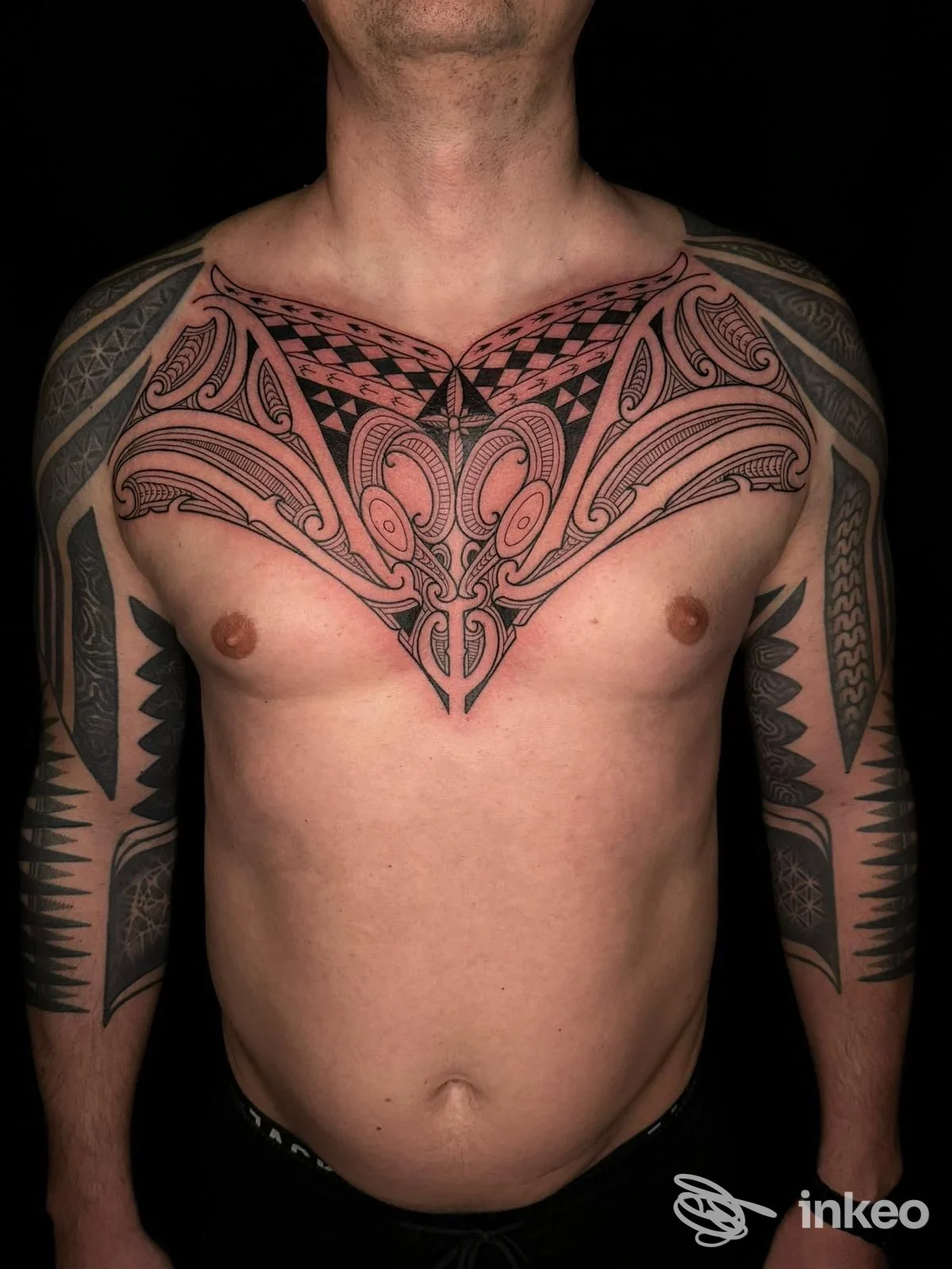 Torace e braccia tatuati con disegno tribale-geometrico in nero e rosso, foto fornita da Soul Moko Tattoo, Santo Stefano di Camastra.