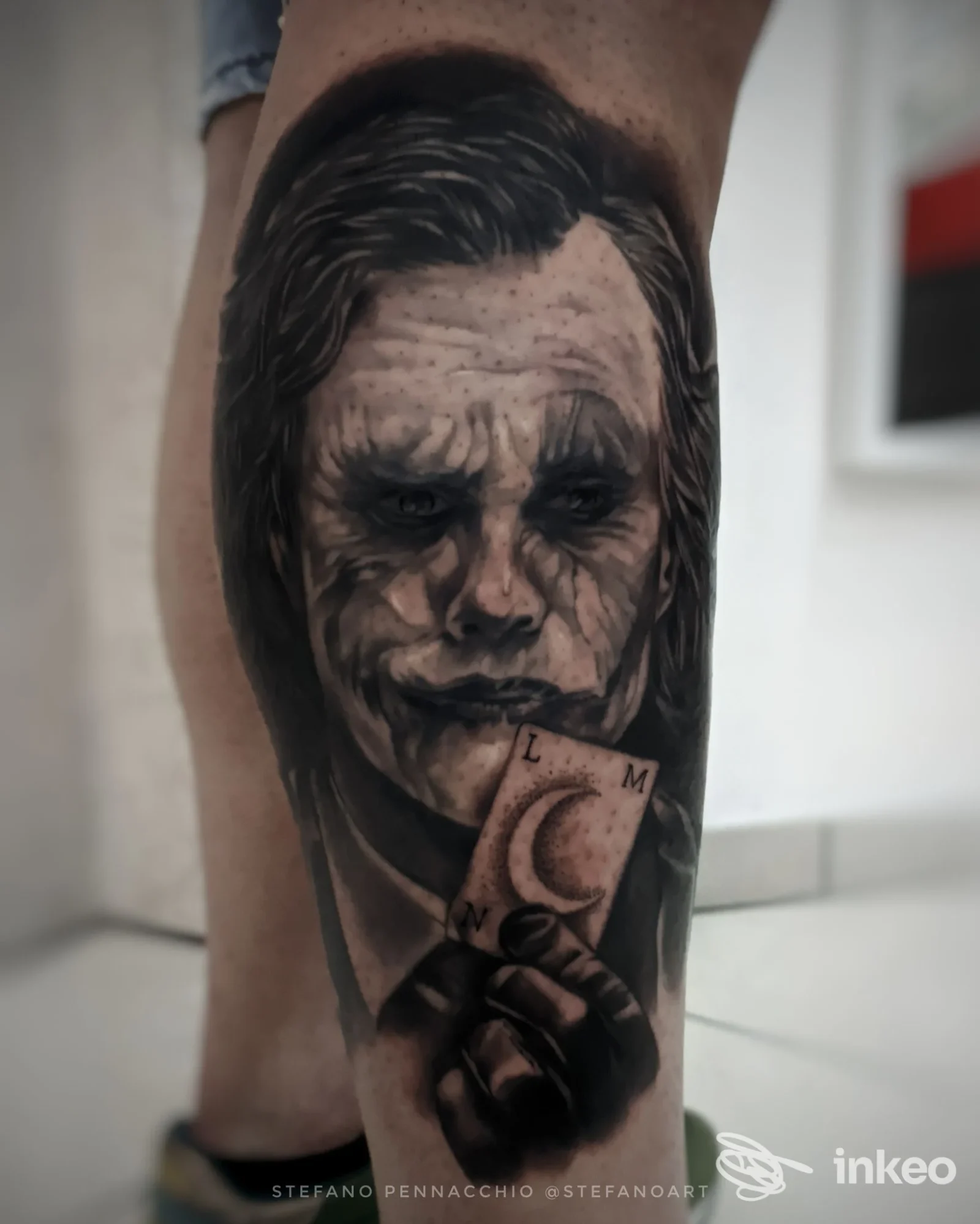 Tatuaggio realistico sul polpaccio: ritratto in bianco e nero che tiene una carta, Tattoo Studio di Stefano Pennacchio, Lentini.
