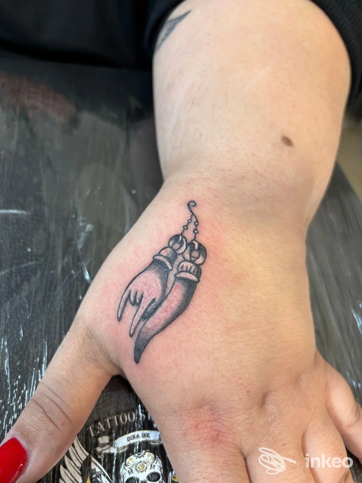 Tatuaggio nero sfumato raffigurante un amuleto sul dorso della mano, fotografato nello studio Tattoo Dinaink ad Acireale.