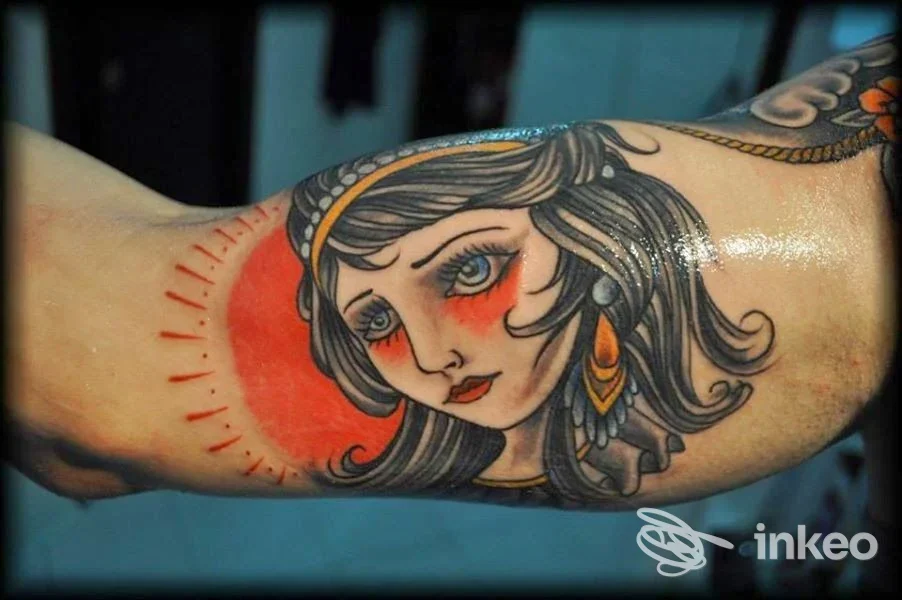 Dettaglio di tatuaggio sul bicipite interno con volto femminile stilizzato e disco rosso, realizzato da Tattoo e Piercing I colori dell'anima, Palermo.