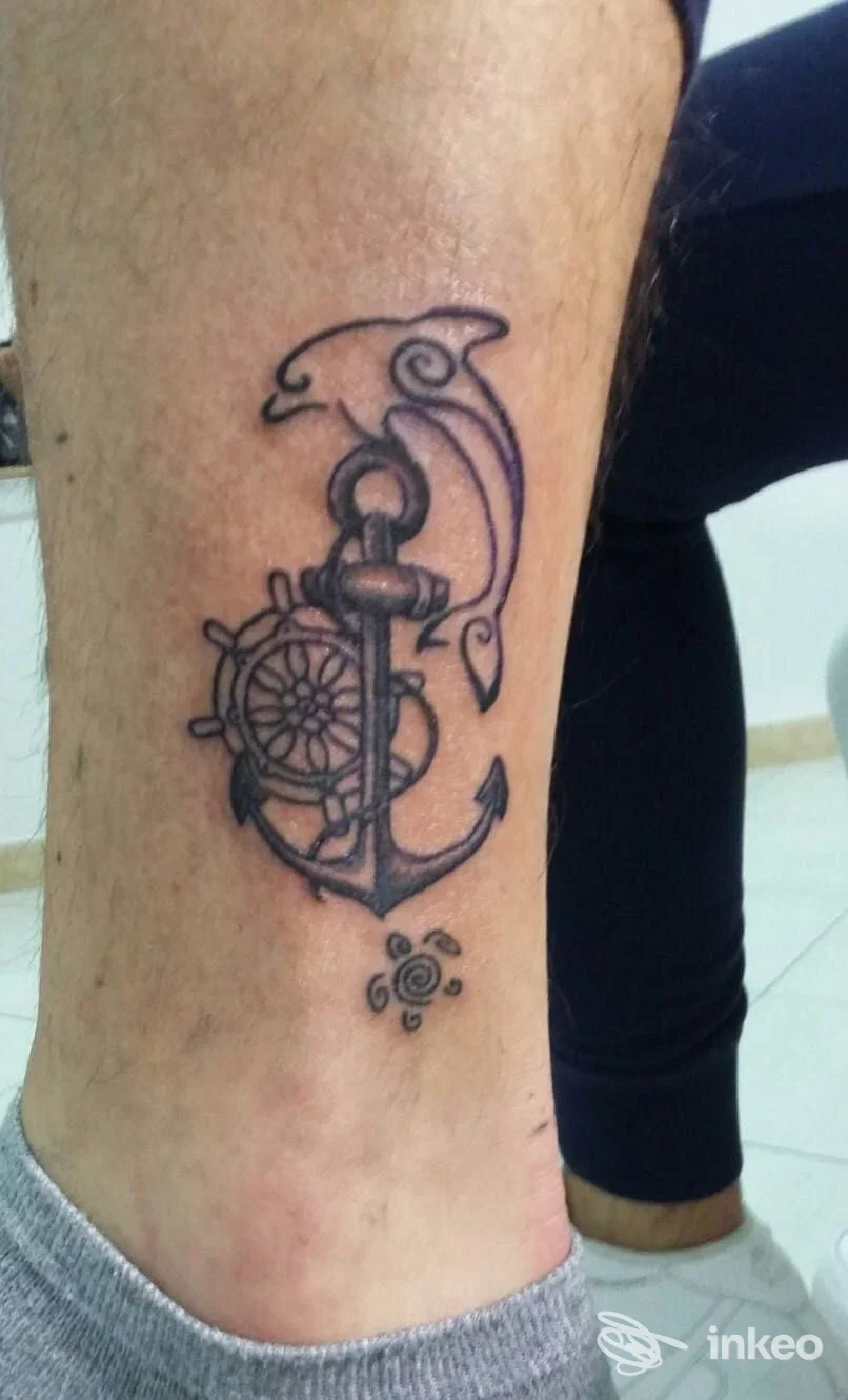 Tatuaggio di ancora, timone e delfino stilizzato sul polpaccio, realizzato da Tattoo time a Sciacca.