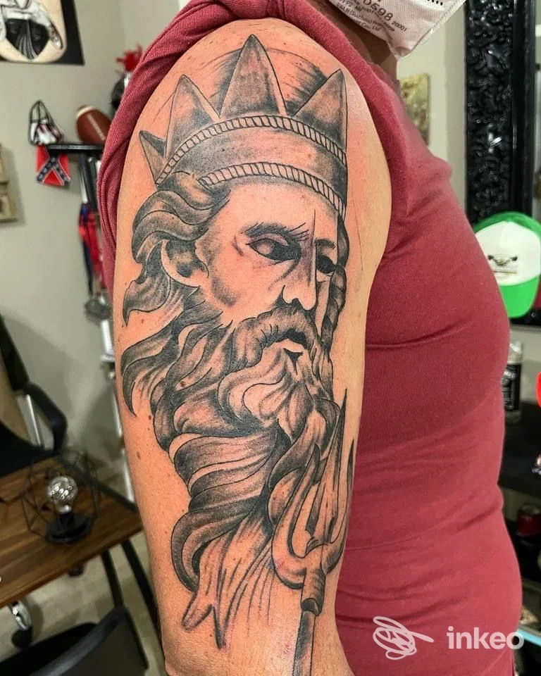 Tatuaggio in bianco e nero di un volto coronato e barbuto sul braccio superiore, Tatuaggi David Ink, Trapani.