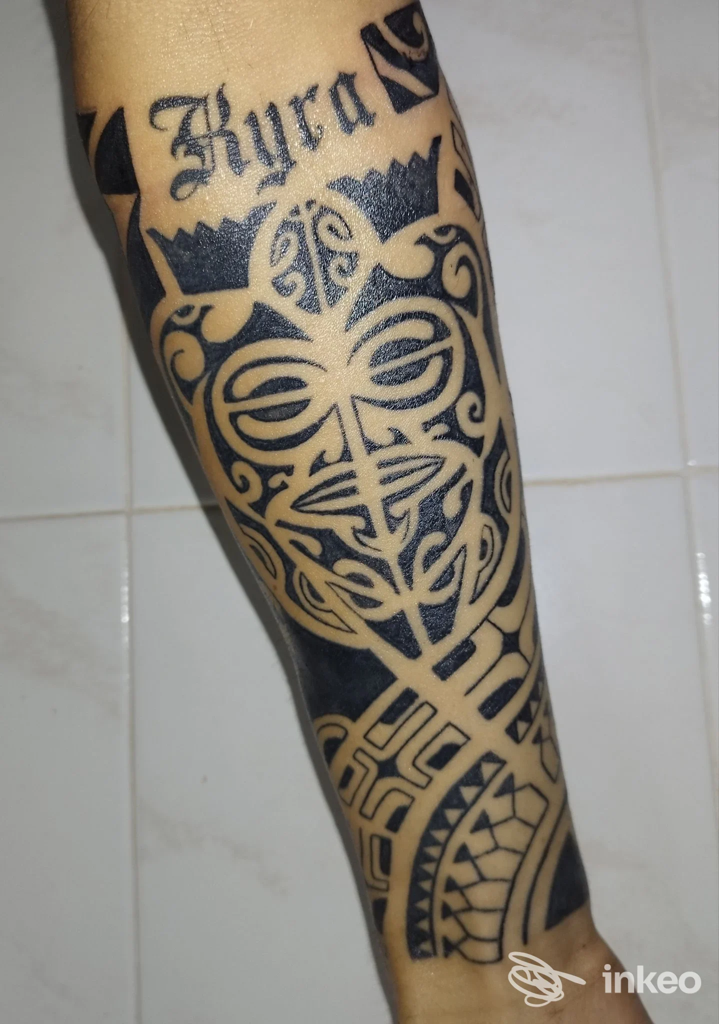 Tatuaggio tribale nero che copre l'avambraccio con la scritta 'Kyra', foto fornita da That's Amore Tattoo Studio a Palermo.