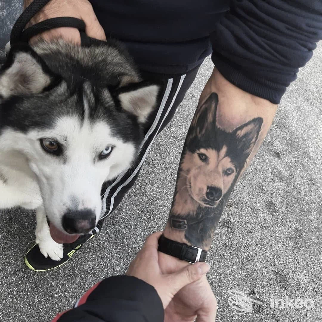 Avambraccio tatuato con ritratto realistico di un husky; foto scattata all'esterno. The Kingdom Tattoo, Cefalù.