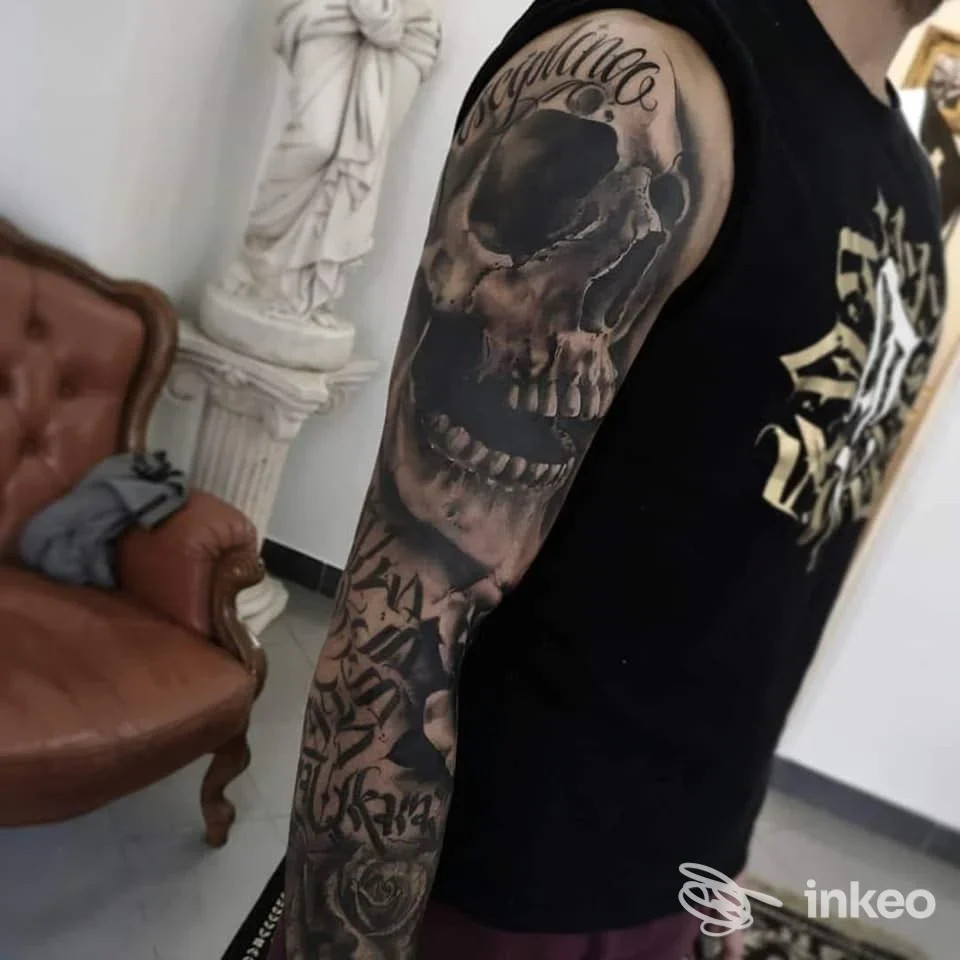 Manica tatuata in bianco e nero con cranio e rose, foto scattata nello studio The Kingdom Tattoo a Cefalù.