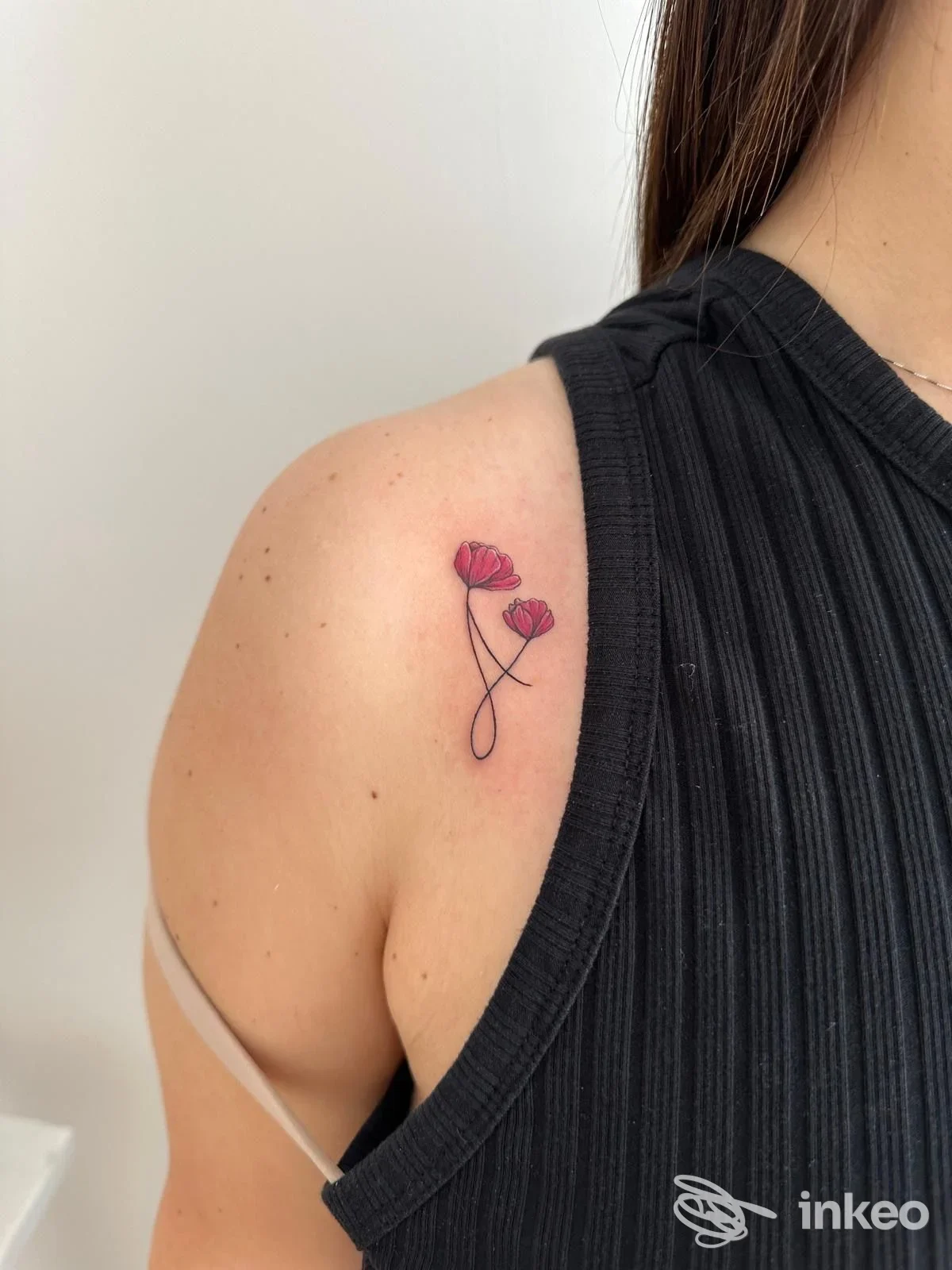 Tatuaggio minimale di due piccoli papaveri rossi sulla spalla fotografato per The Odyssey Tattoo a Trapani.