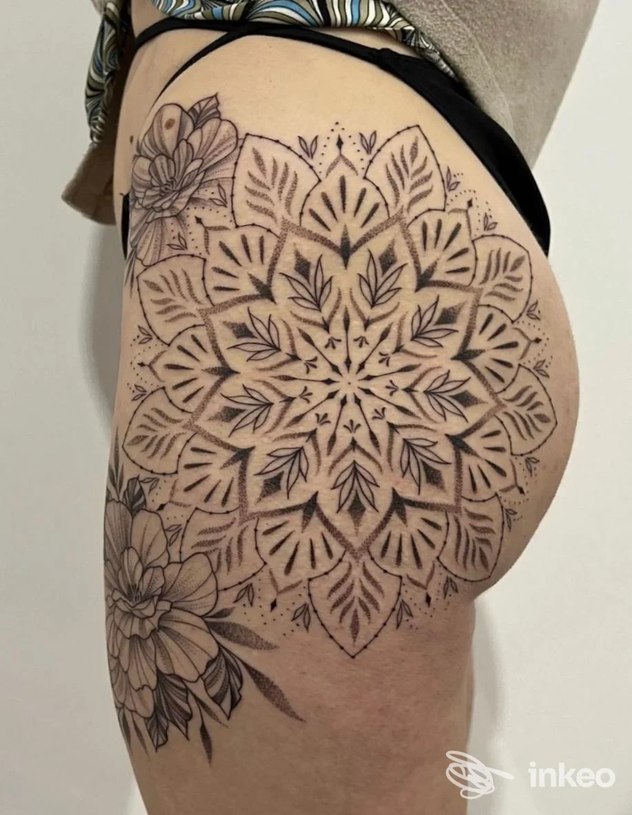 Grande mandala nero con fiori tatuato sull'anca e la parte superiore della coscia, lavoro mostrato da Torture Tattoo Studio a Milazzo.