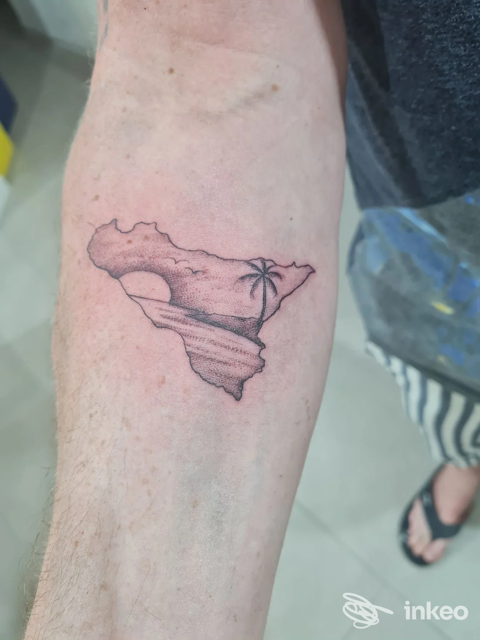 Tatuaggio a inchiostro nero su avambraccio interno che raffigura una sagoma con paesaggio marino. Vintage tattoo sopra il porto, Terrasini.