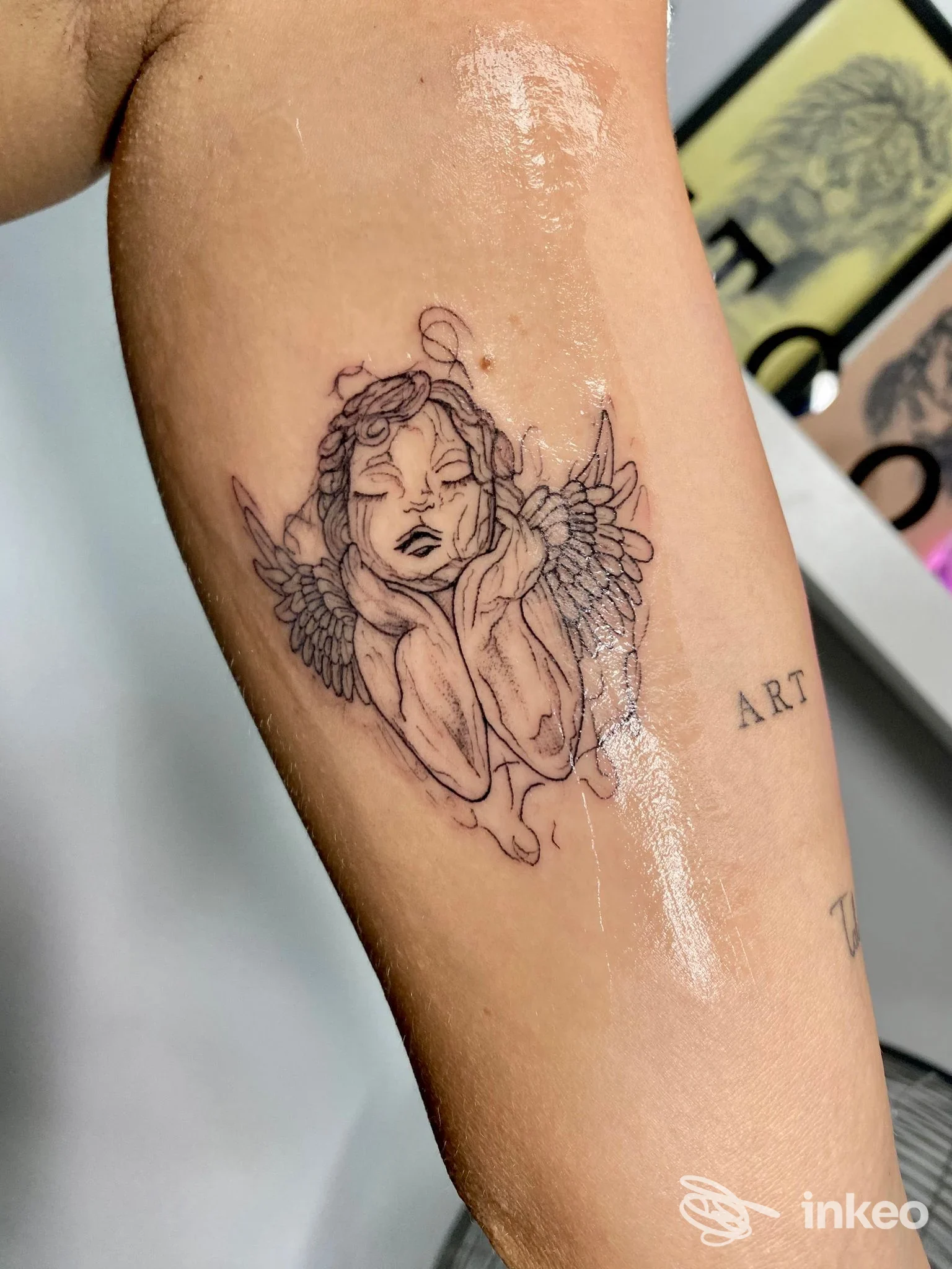 Tatuaggio linework di un cherubino sull'avambraccio, scatto nello studio Wanderlust Tattoo di Maria Vanessa Alotto a Palma di Montechiaro.