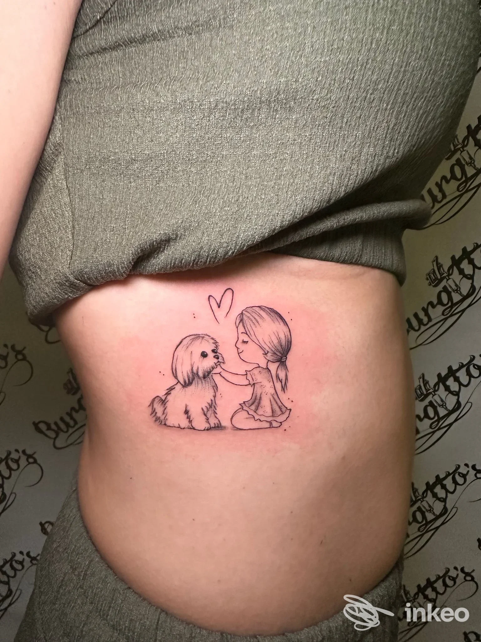 Tatuaggio su fianco raffigurante una bambina che accarezza un cane, foto fornita da Burgitto's Tattoo Studio, Giarre.