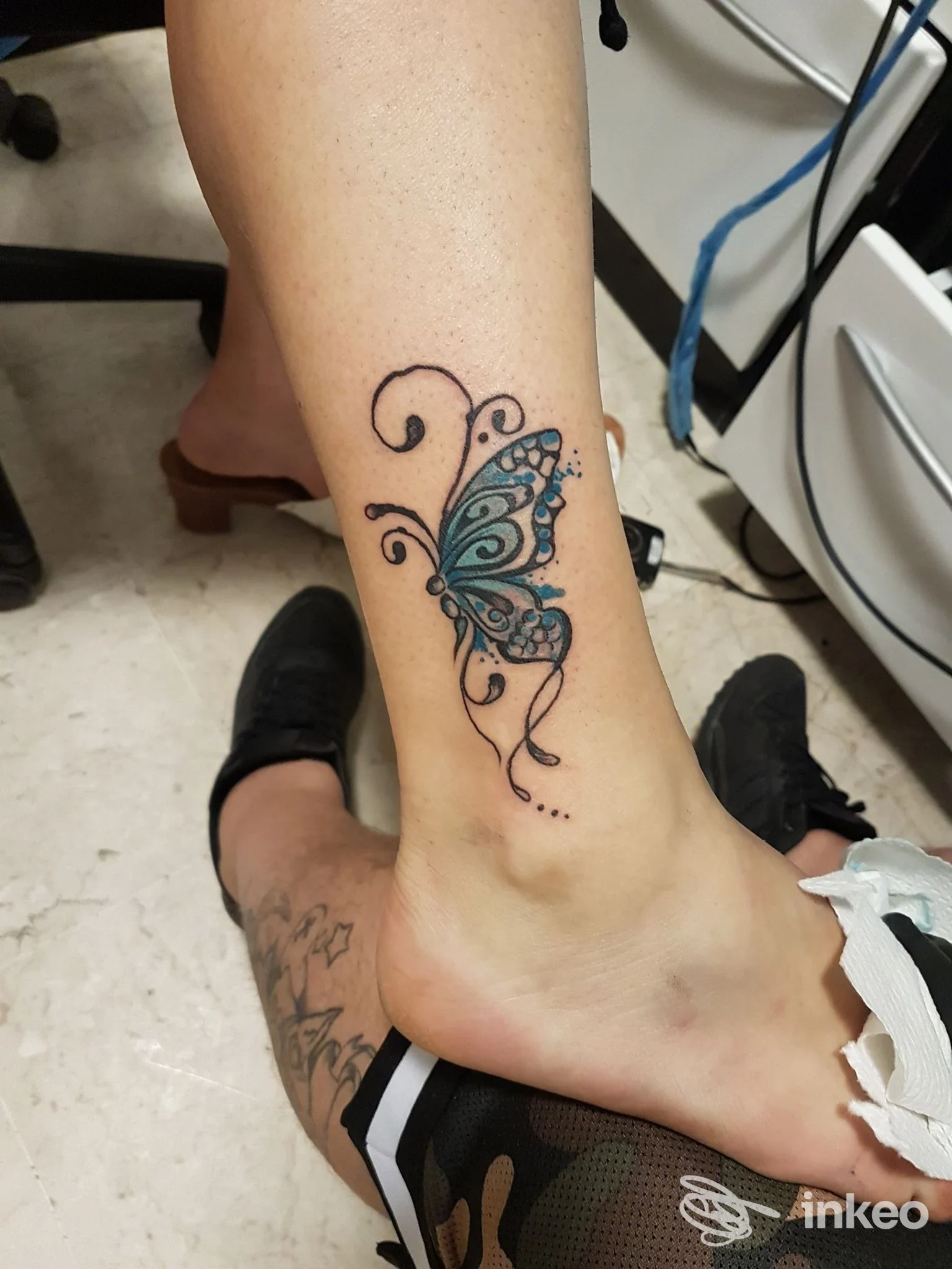 Fotografia di un tatuaggio a farfalla colorata sulla caviglia e parte inferiore della gamba, realizzato da Egizio Tattoo a Palermo.