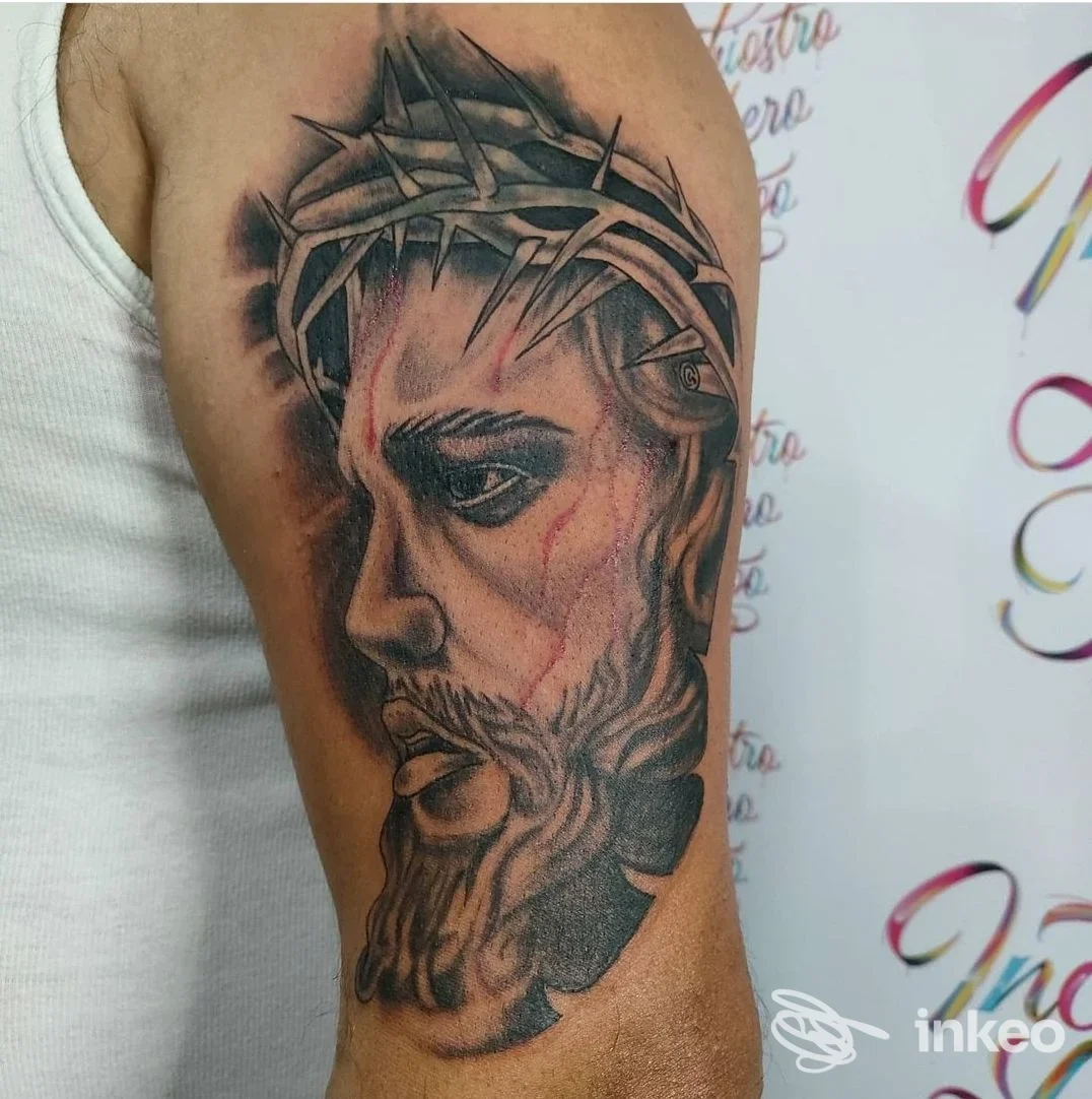 Tatuaggio realistico di un volto con corona di spine sull'alto braccio, foto dello studio Inchiostro Libero Studio Tattoo a Partinico.