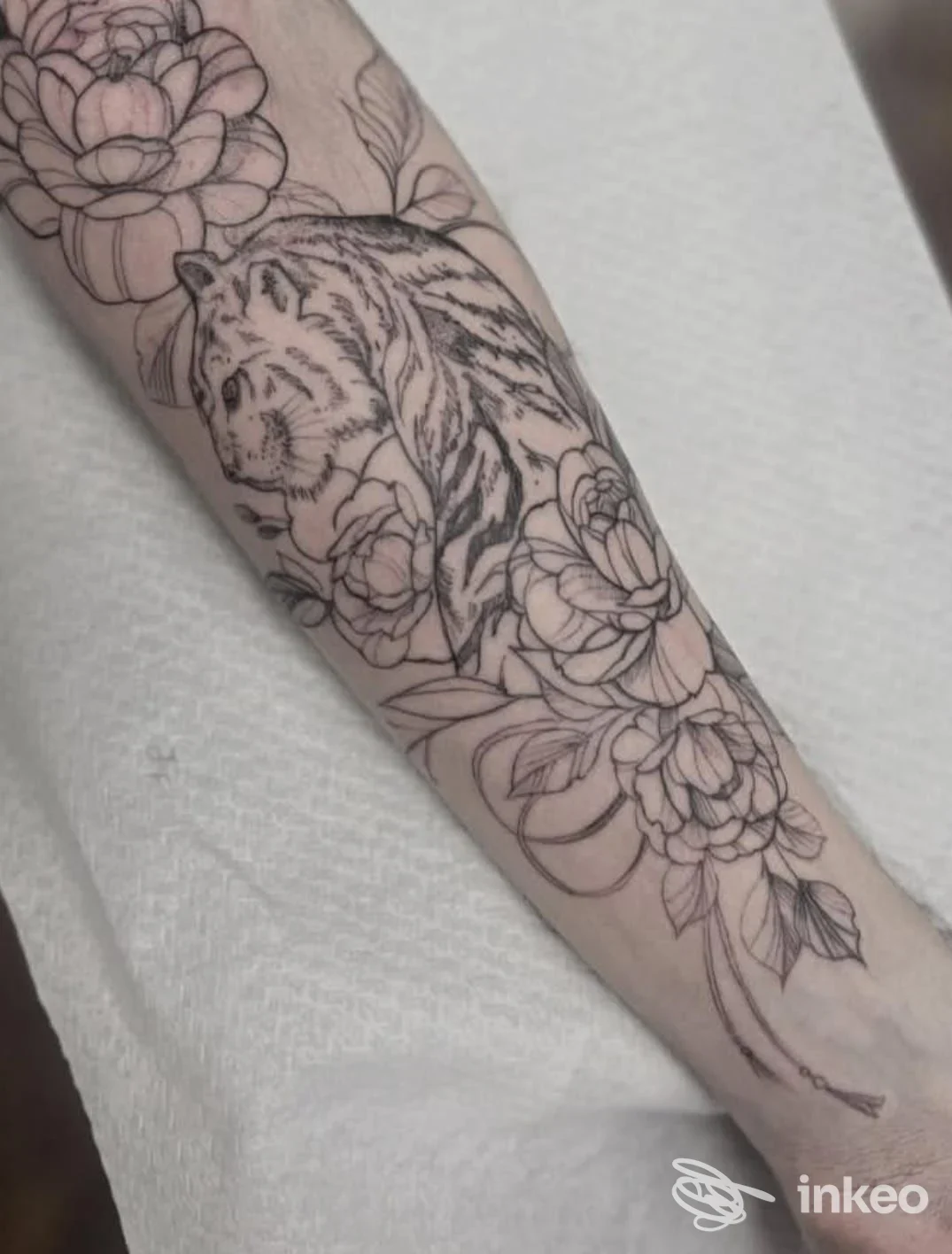 Tatuaggio a linee di una tigre circondata da fiori sull'avambraccio, foto di progetto eseguito da Laurita Sharpz - Tattoo & Art studio, Palermo.
