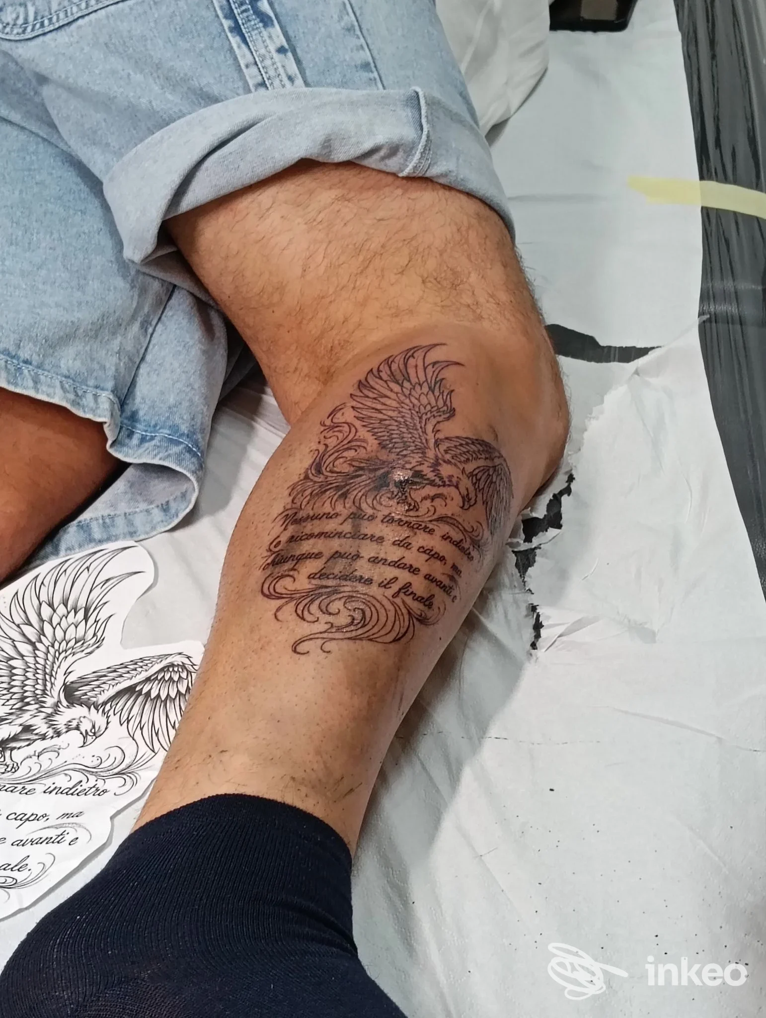 Polpaccio con tatuaggio di un uccello stilizzato sopra una citazione, foto fornita da Metamorfosi Tattoo studio di Santo Campagna a Pace del Mela.
