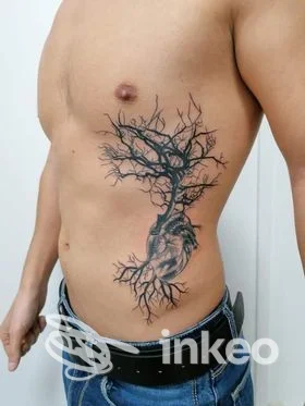 Grande tatuaggio nero a forma di albero che confluisce in un cuore anatomico sul fianco di un torace maschile. Pablo Tattoo, Agrigento.