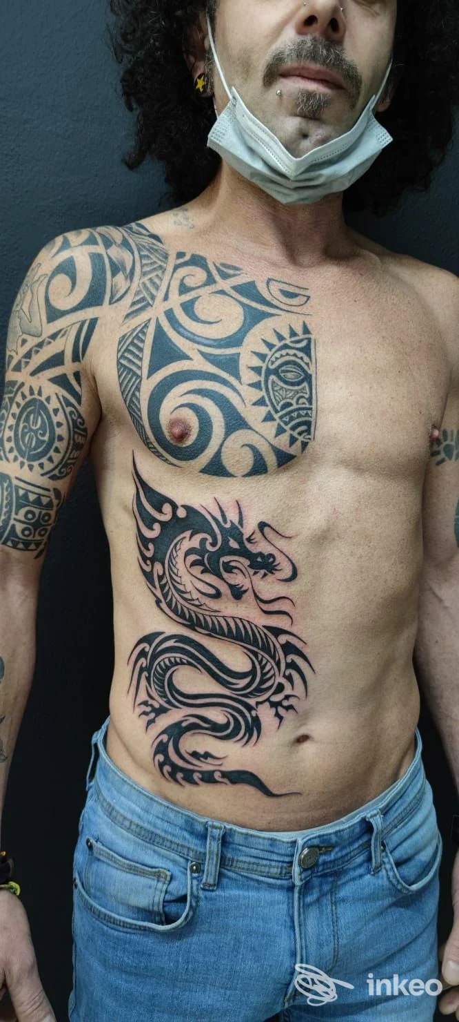 Uomo con ampio tatuaggio tribale nero su torace, spalla e fianco; World Art Tattoo, Caltagirone.
