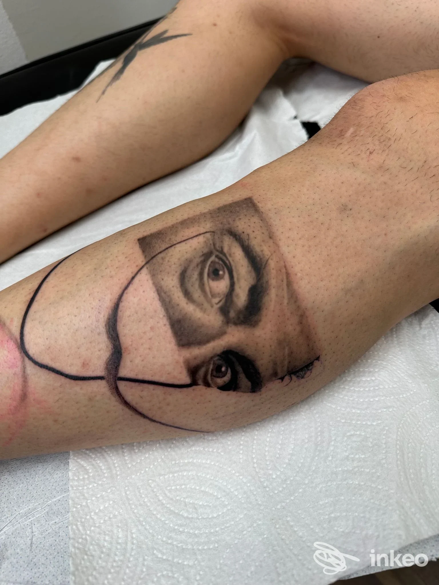 Tatuaggio realistico in black & grey con occhi e frammento di volto sul polpaccio, Gloma Tattoo Artist, Peccioli.
