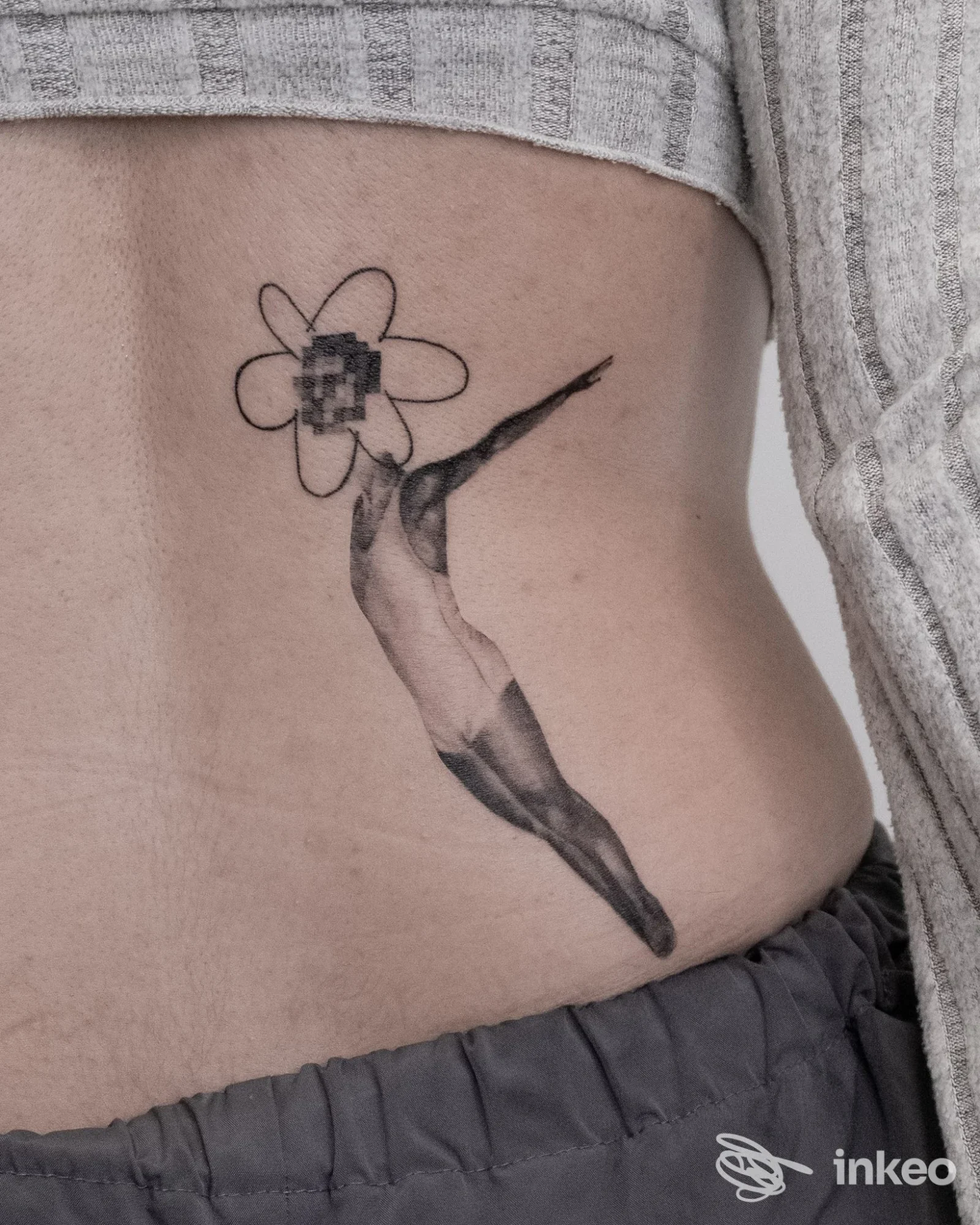 Tatuaggio sul fianco raffigurante una figura in tuffo verso un fiore stilizzato, foto per Gloma Tattoo Artist, Peccioli.