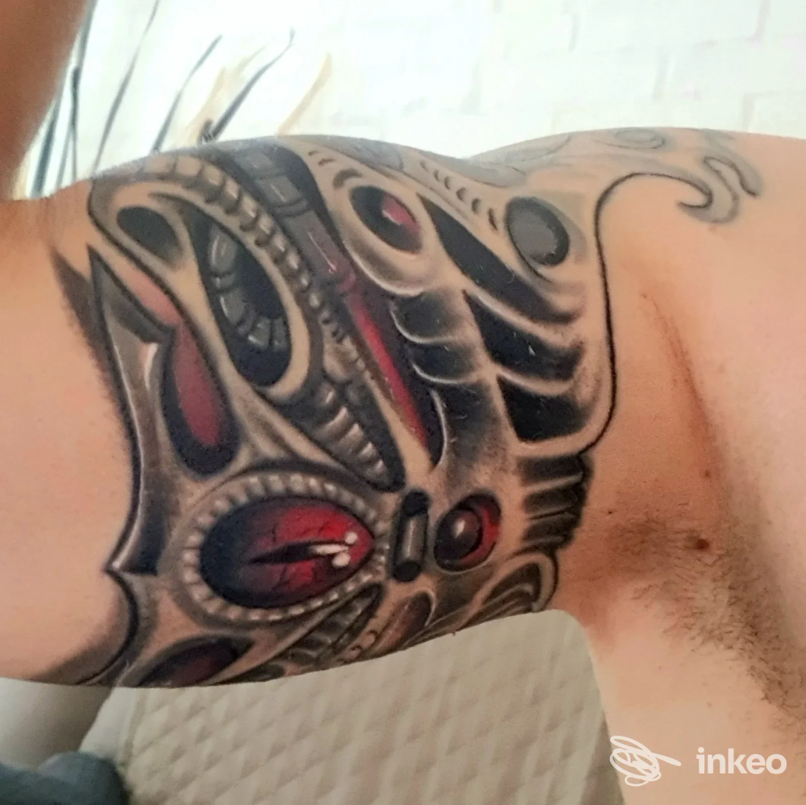 Tatuaggio ornato su braccio realizzato sulla pelle; fotografia singola evidenzia una grafica nera con dettagli rossi, senza volto visibile e senza watermark o testo estraneo.