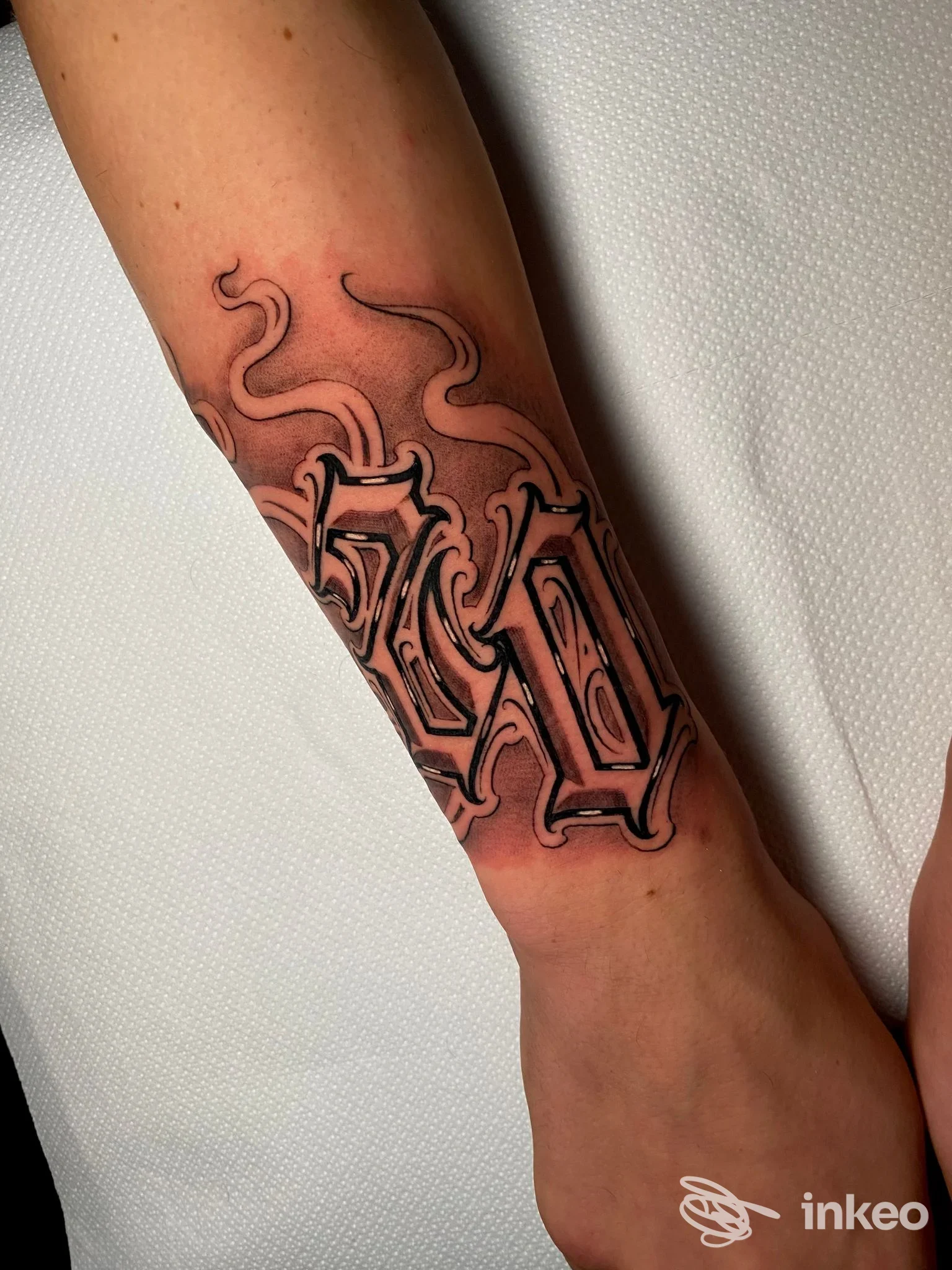 Tatuaggio lettering in nero e grigio sull'avambraccio, realizzato da Hoodgang Tattoo Studio a Montale, dettagli e ombreggiature nette.