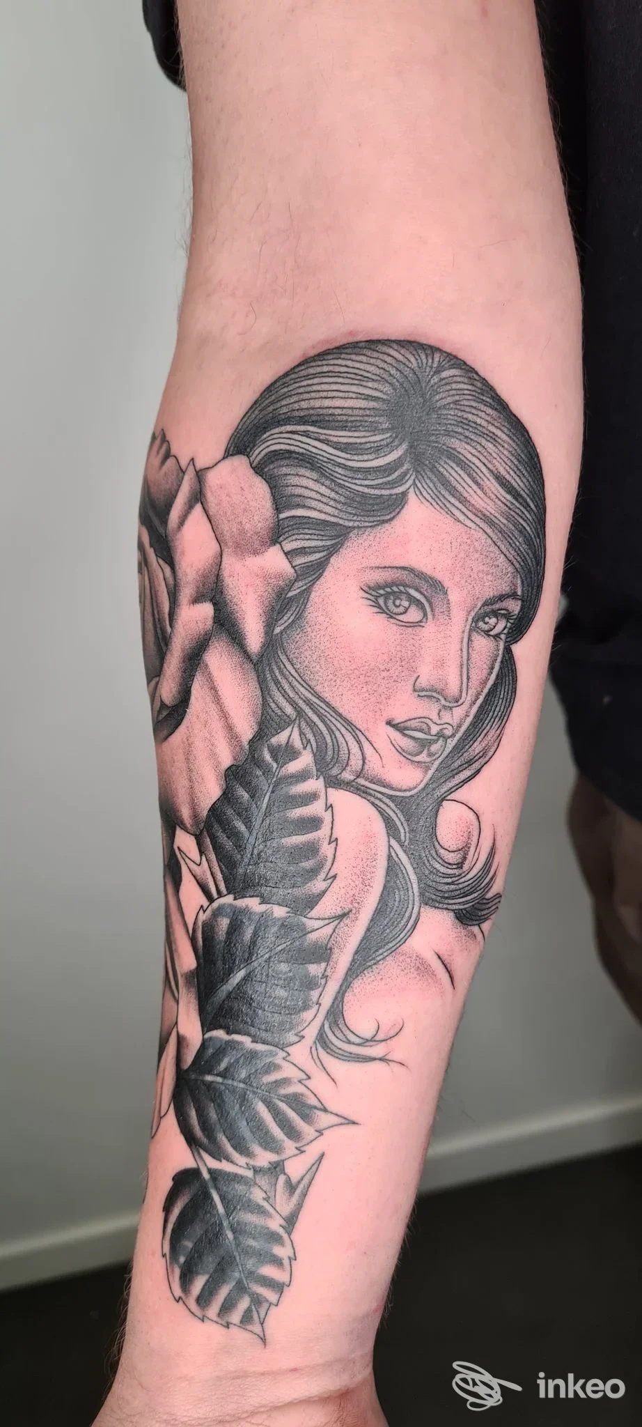 Tatuaggio in bianco e nero sull'avambraccio con ritratto femminile e foglie, realizzato da INKSPIRITO TATTOO ad Arezzo.