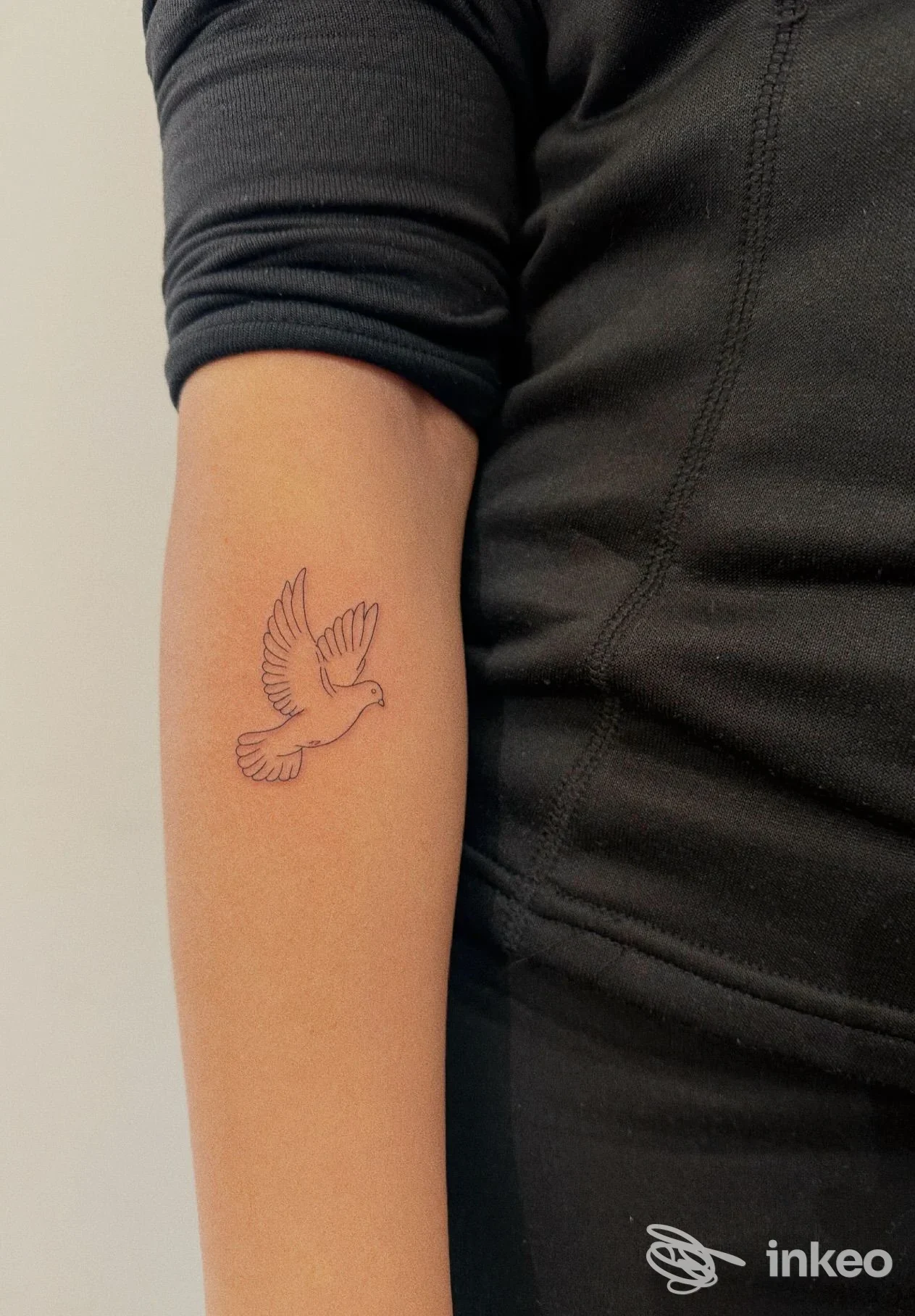 Piccolo tatuaggio a linea di una colomba sull'avambraccio interno, foto inviata da Ikigai Tattoo Studio, Firenze.