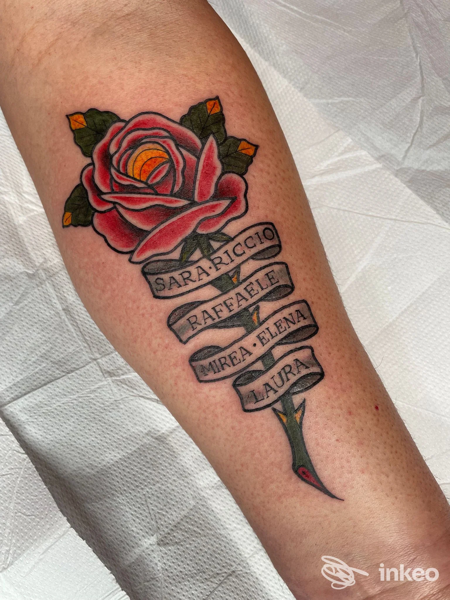 Tatuaggio rosa con nastro nominativo sull'avambraccio, eseguito da Holy Ink Tattoo Atelier Firenze.