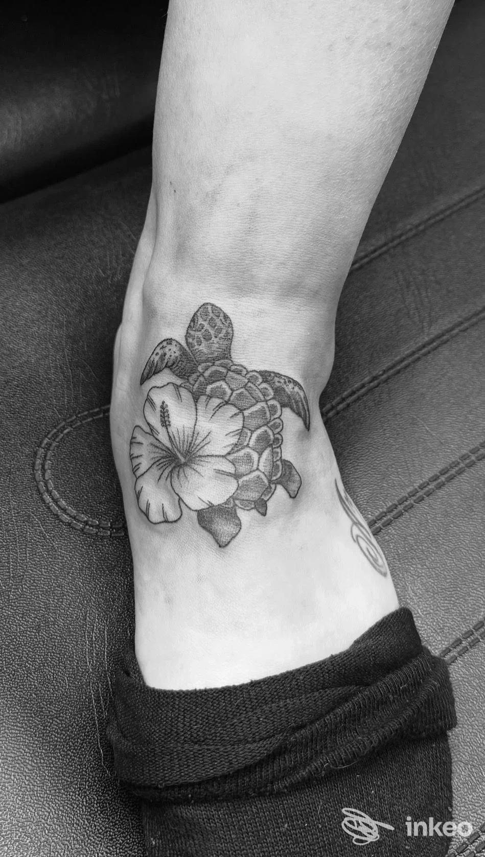 Tatuaggio tartaruga con fiore sulla caviglia, realizzato da Inke Tattoo & Piercing a Capannori.