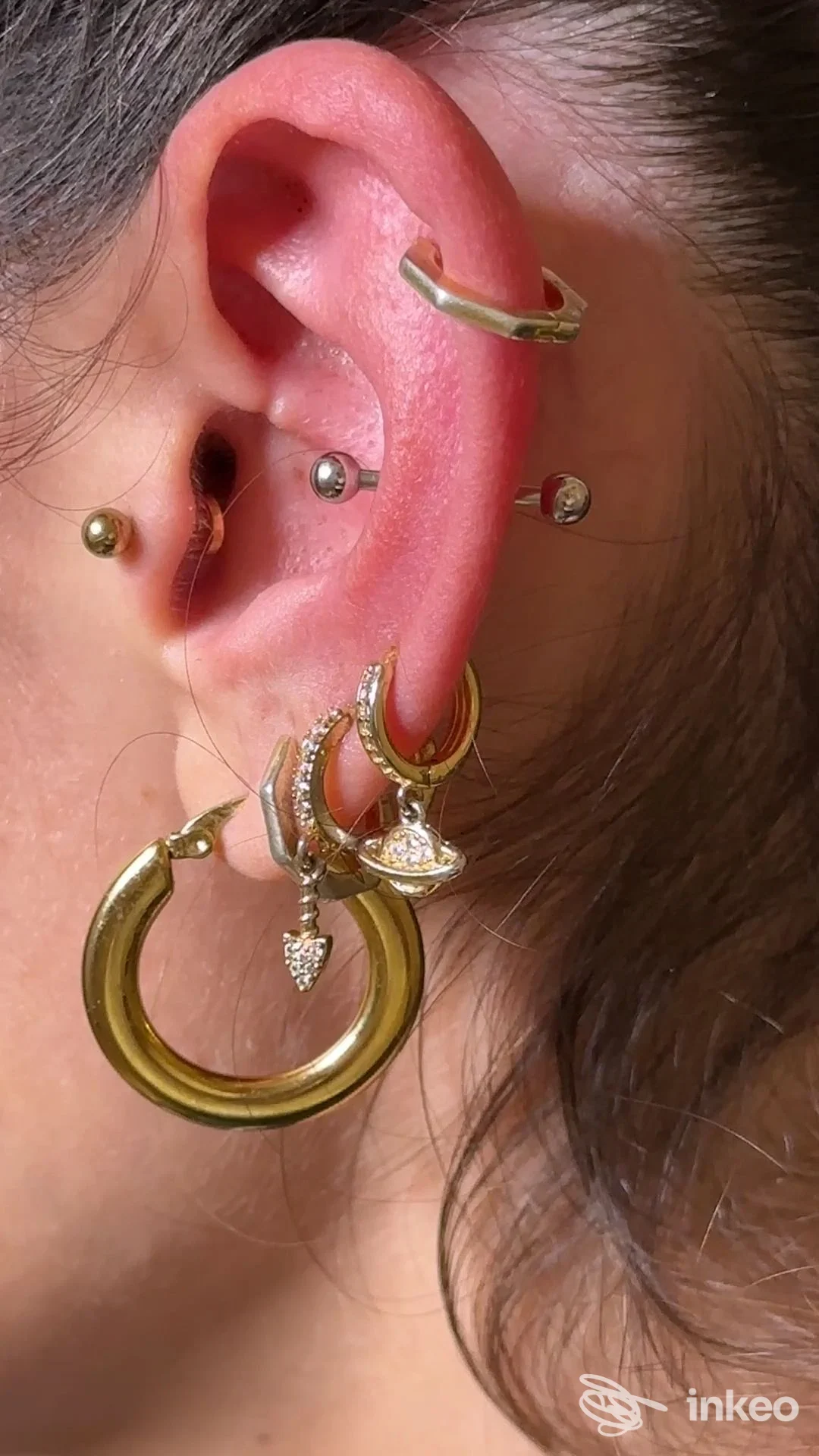 Primo piano di un orecchio con più piercing e gioielli dorati, foto inviata da La Belle Studio Tattoo&Piercing, Pescia.