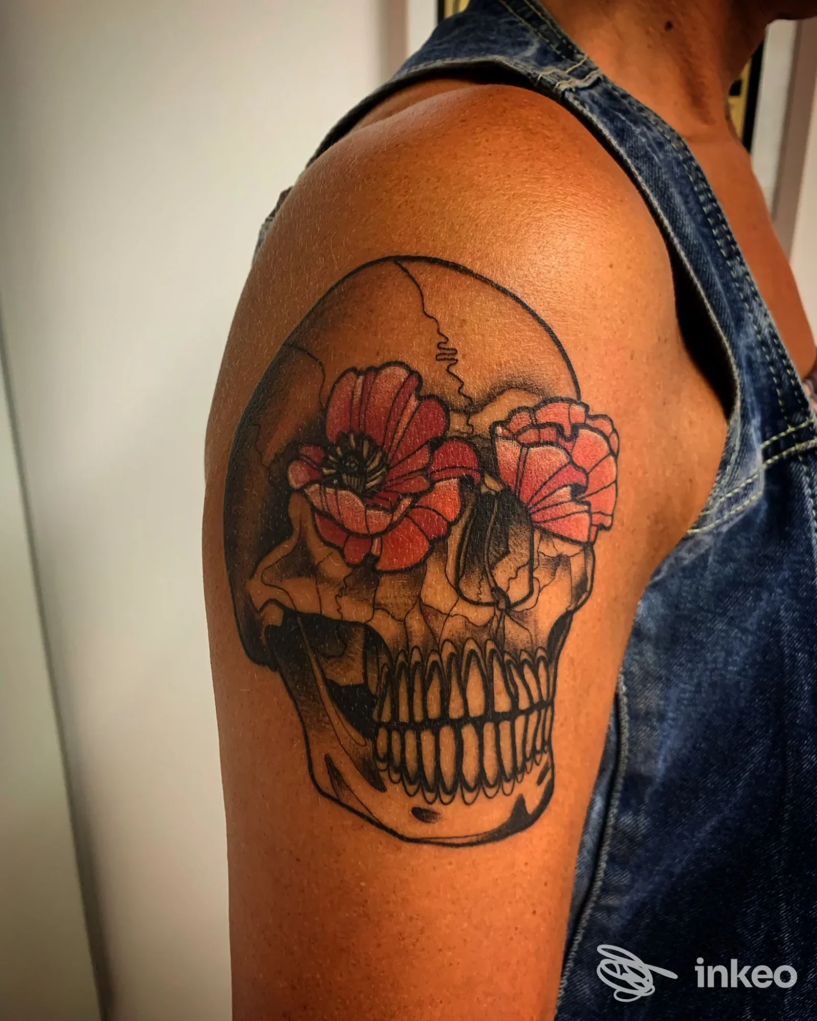 Tatuaggio a forma di teschio con fiori sulla parte superiore del braccio, foto fornita da La Torre dei Diavoli Tattoo Studio, Poppi.