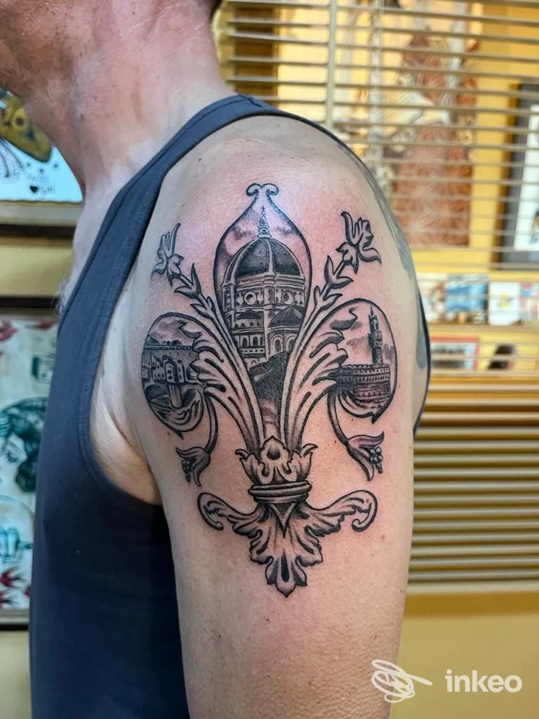 Tatuaggio a giglio con scene architettoniche sul deltoide, foto fornita da Little Dipper Tattoo, Scandicci.