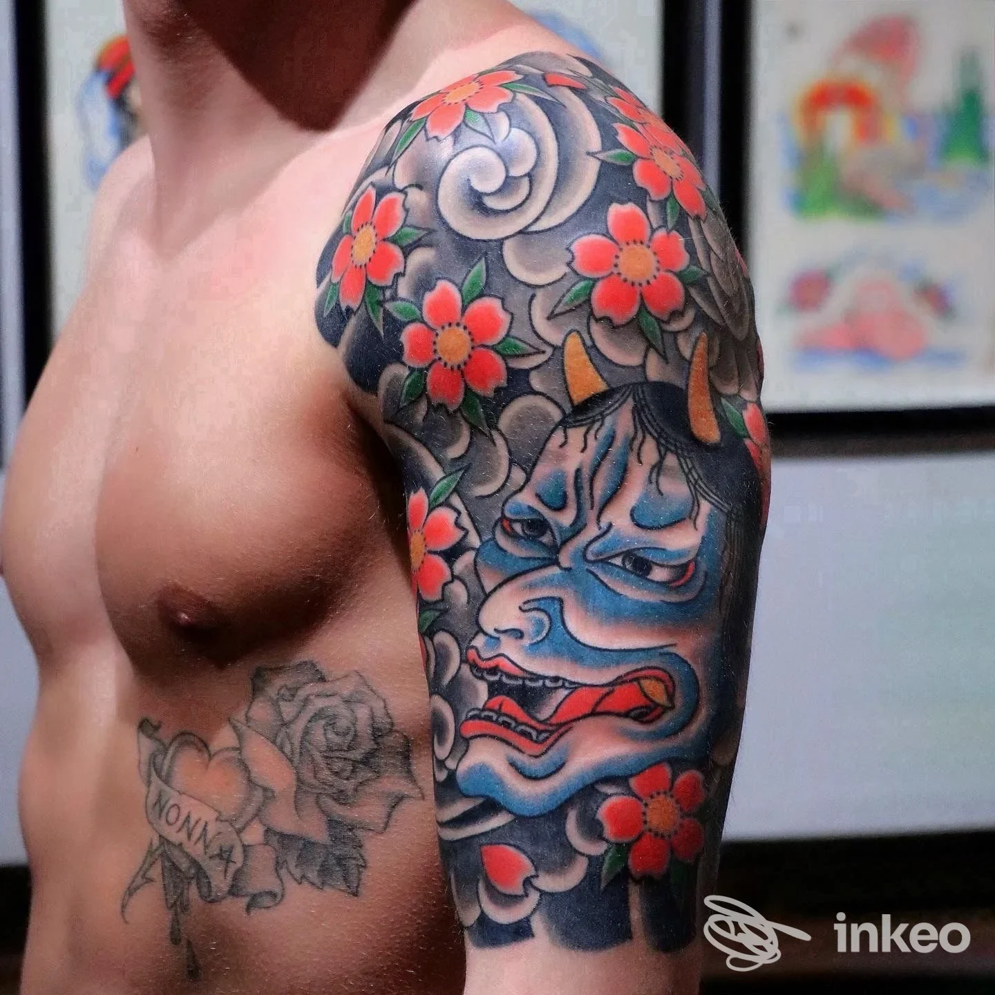 Tatuaggio a mezza manica in stile giapponese con maschera oni, nuvole e fiori rossi sulla spalla e braccio superiore, foto inviata da Lo Studiolo Tattoo & Art Gallery, Firenze.