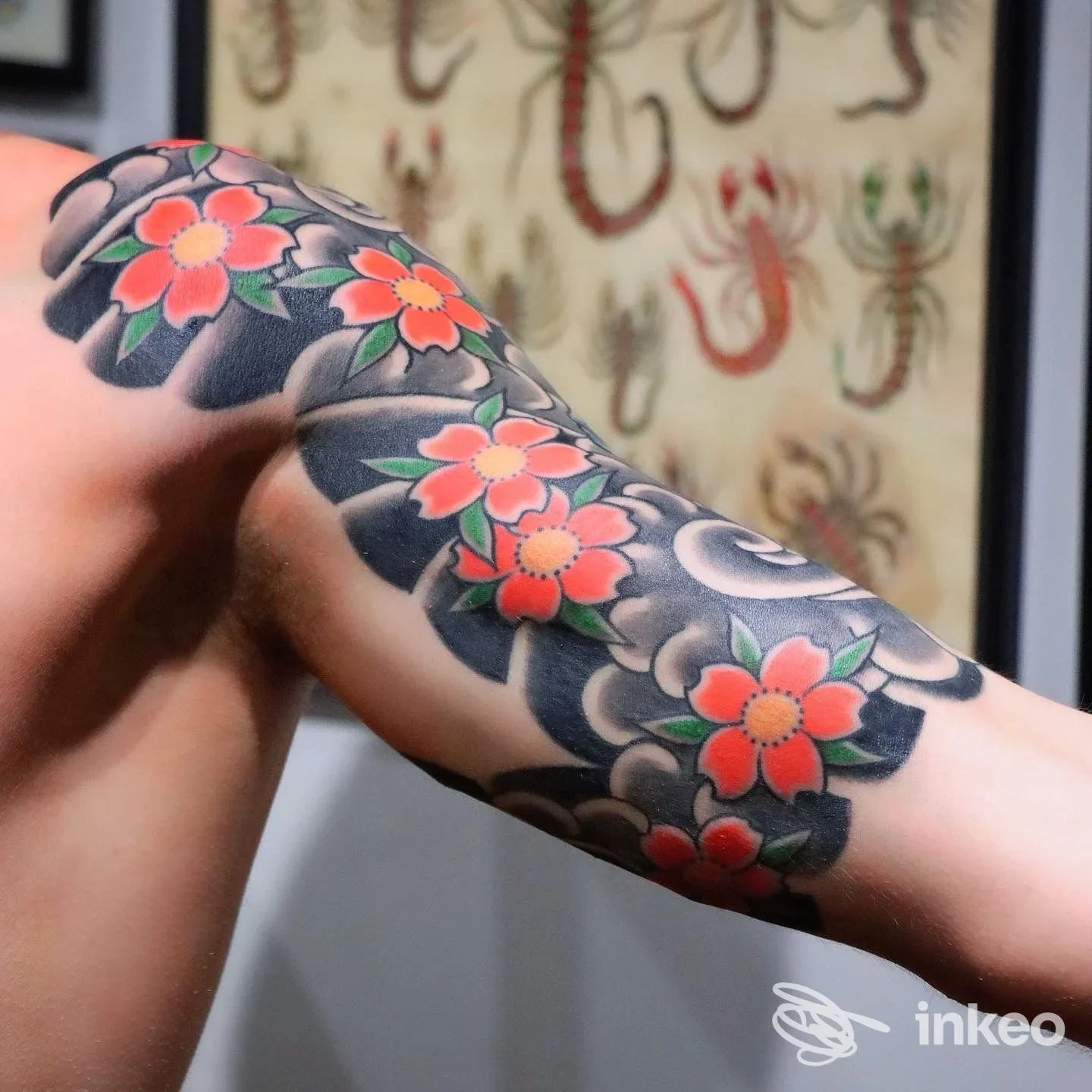 Manica tatuata con fiori rossi e sfondo scuro, scatto in studio Lo Studiolo Tattoo & Art Gallery, Firenze.