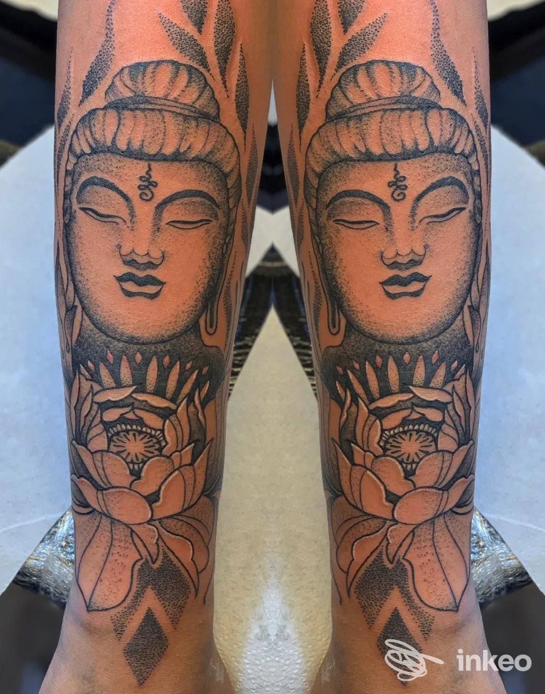 Due avambracci con tatuaggi speculari raffiguranti un volto Buddha e fiori di loto, foto dello studio Loscafamily Tattoo Piercing a Camucia.