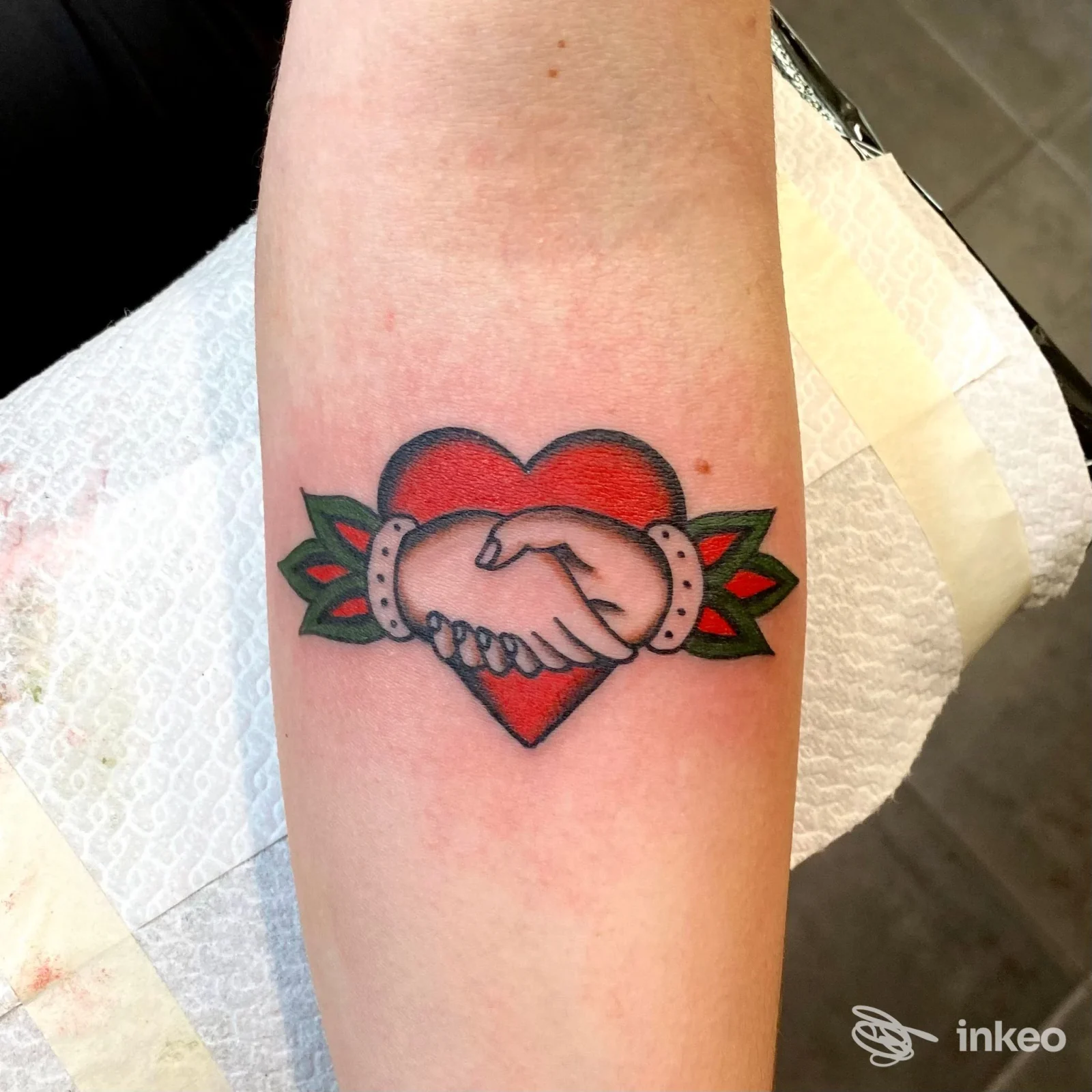 Tatuaggio tradizionale su avambraccio: cuore rosso con due mani che si stringono, Luci Bart Tattoo - Follonica.