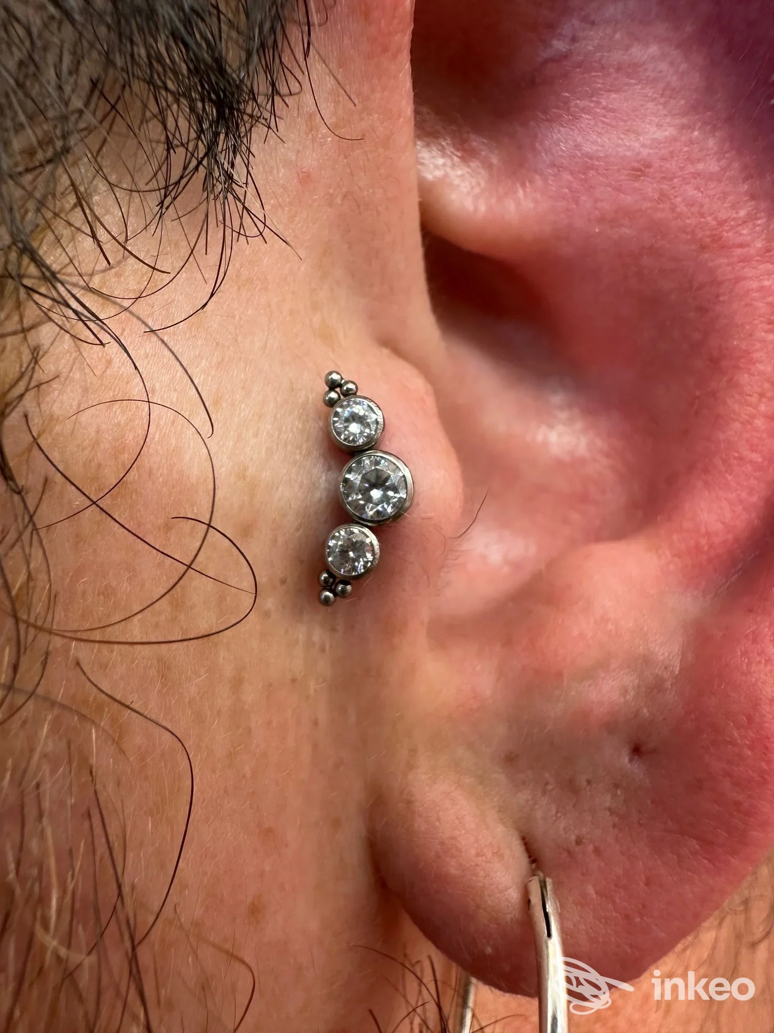 Primo piano di un piercing alla conca con tre gemme, foto fornita da Magnus Piercer, Sesto Fiorentino.