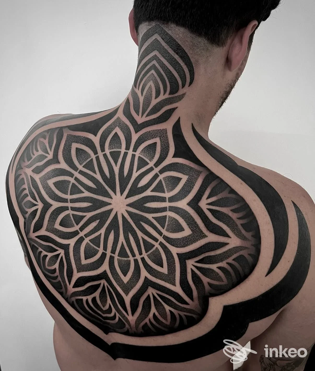 Grande tatuaggio ornamentale e geometrico sulla parte superiore della schiena e nuca, foto fornita da Mano Viva Tattoo Club Firenze, Firenze.
