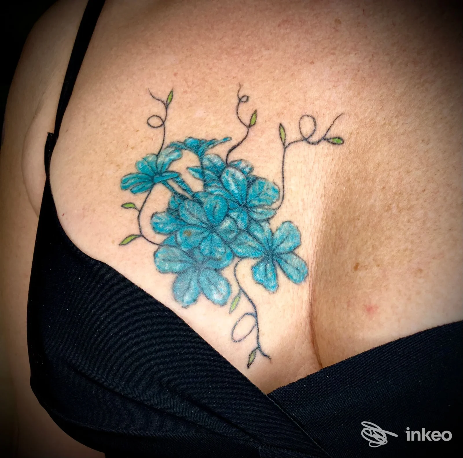 Tatuaggio floreale blu sul décolleté fotografato dallo studio Maya Boll Art & Tattoo a Firenze.