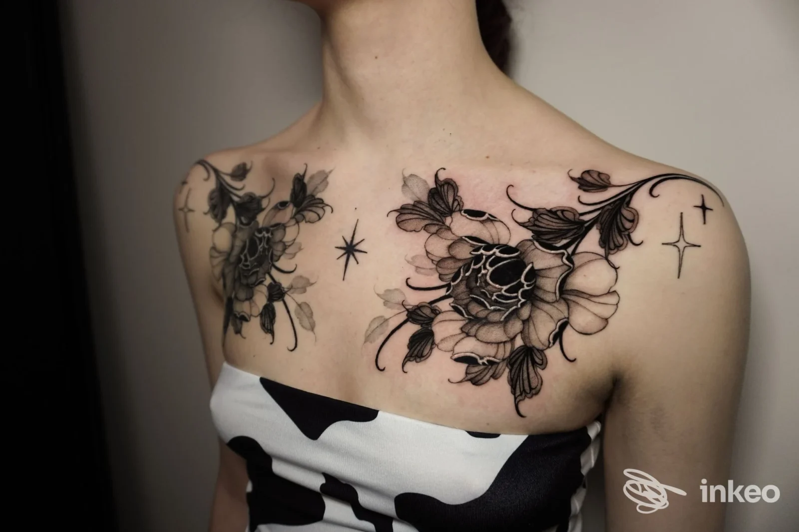 Tatuaggi floreali in nero sul petto e spalle di una persona, lavoro fotografato in studio a Firenze.