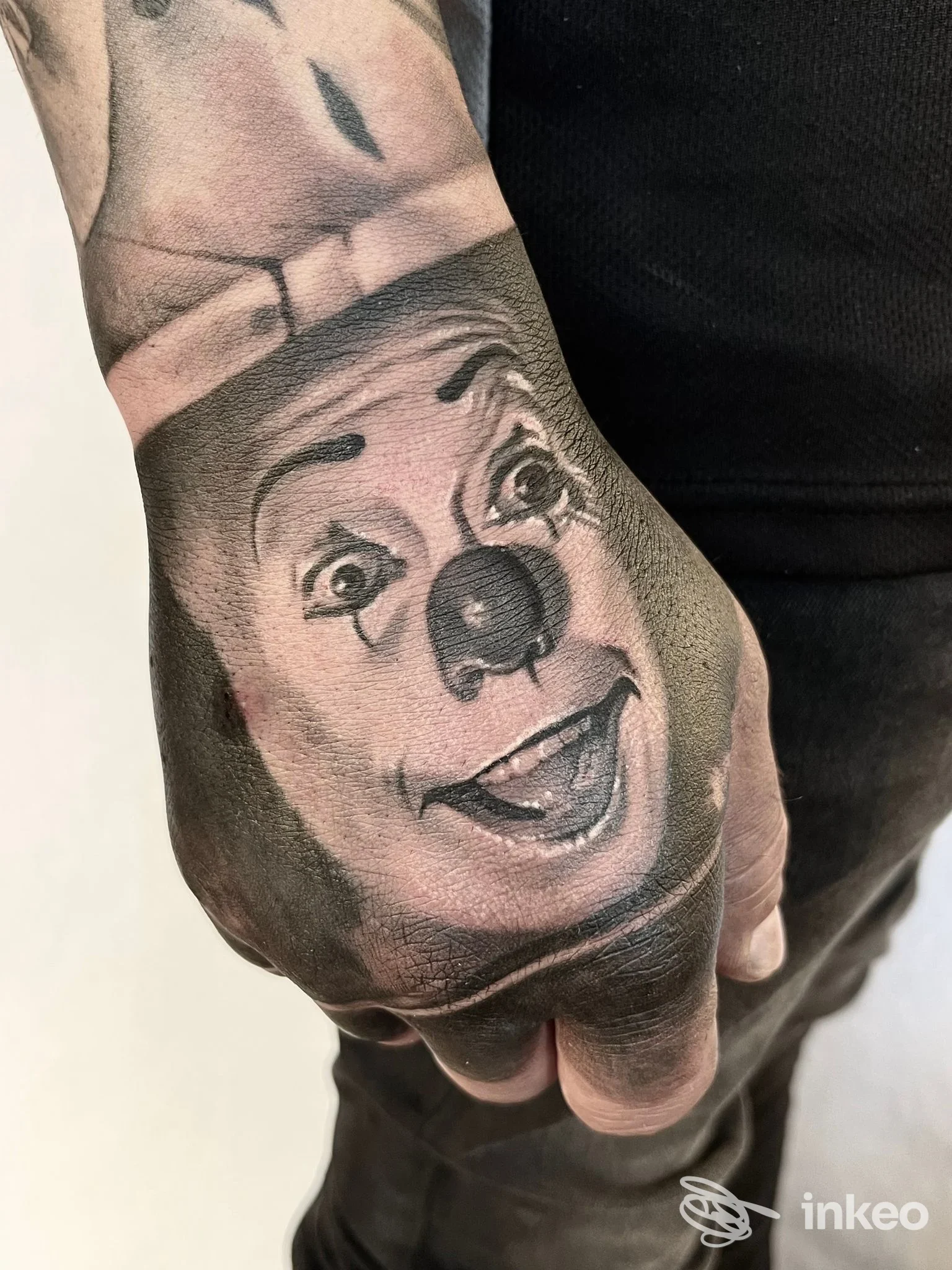 Tatuaggio realistico di un volto di pagliaccio sul dorso della mano, Nocturno Tattoo, Cecina.