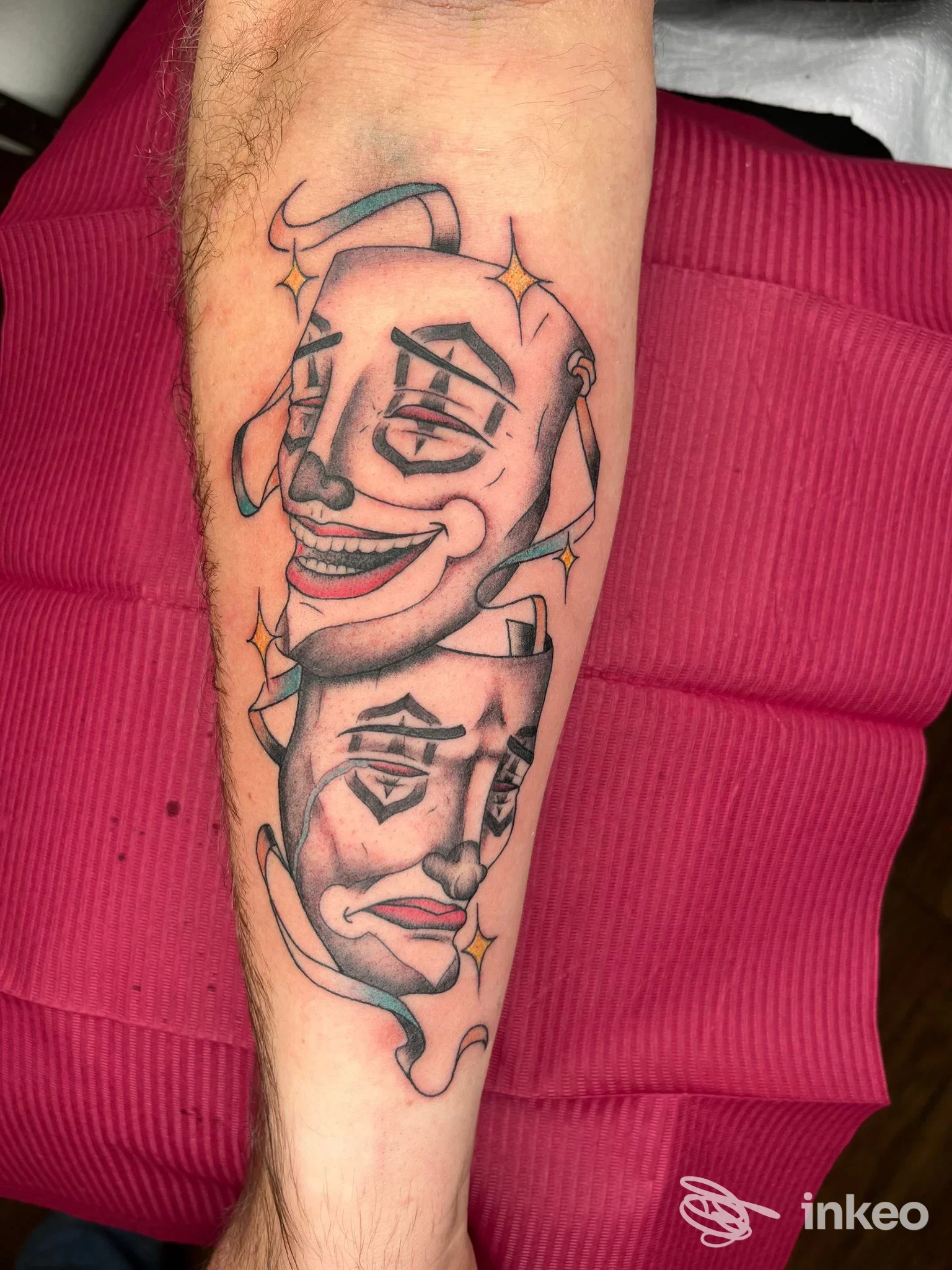 Tatuaggio sull'avambraccio con due maschere stilizzate in nero e ombreggiature, fotografia di NEDO TATTOO a Camaiore.