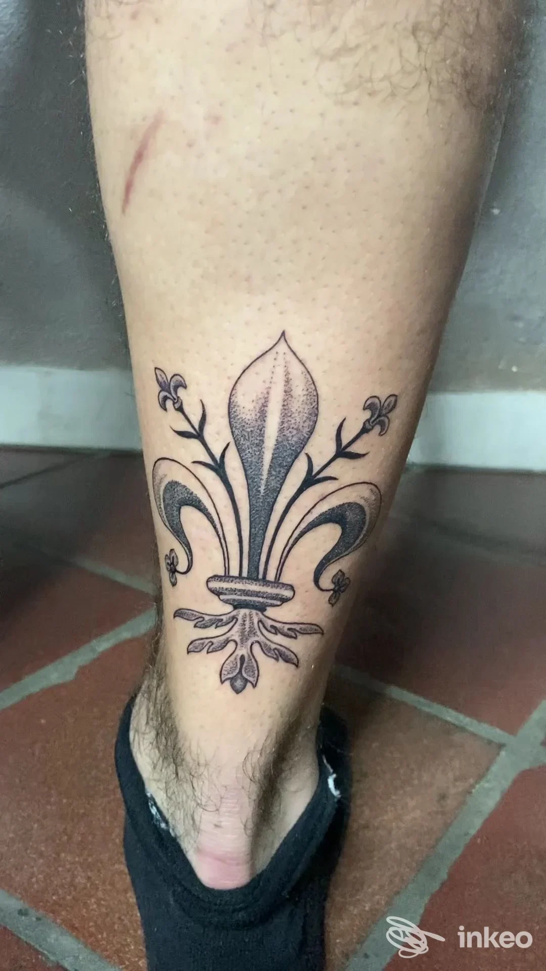 Tatuaggio fleur-de-lis in nero sul polpaccio, realizzato da NeroPerla tattoo a Firenze.