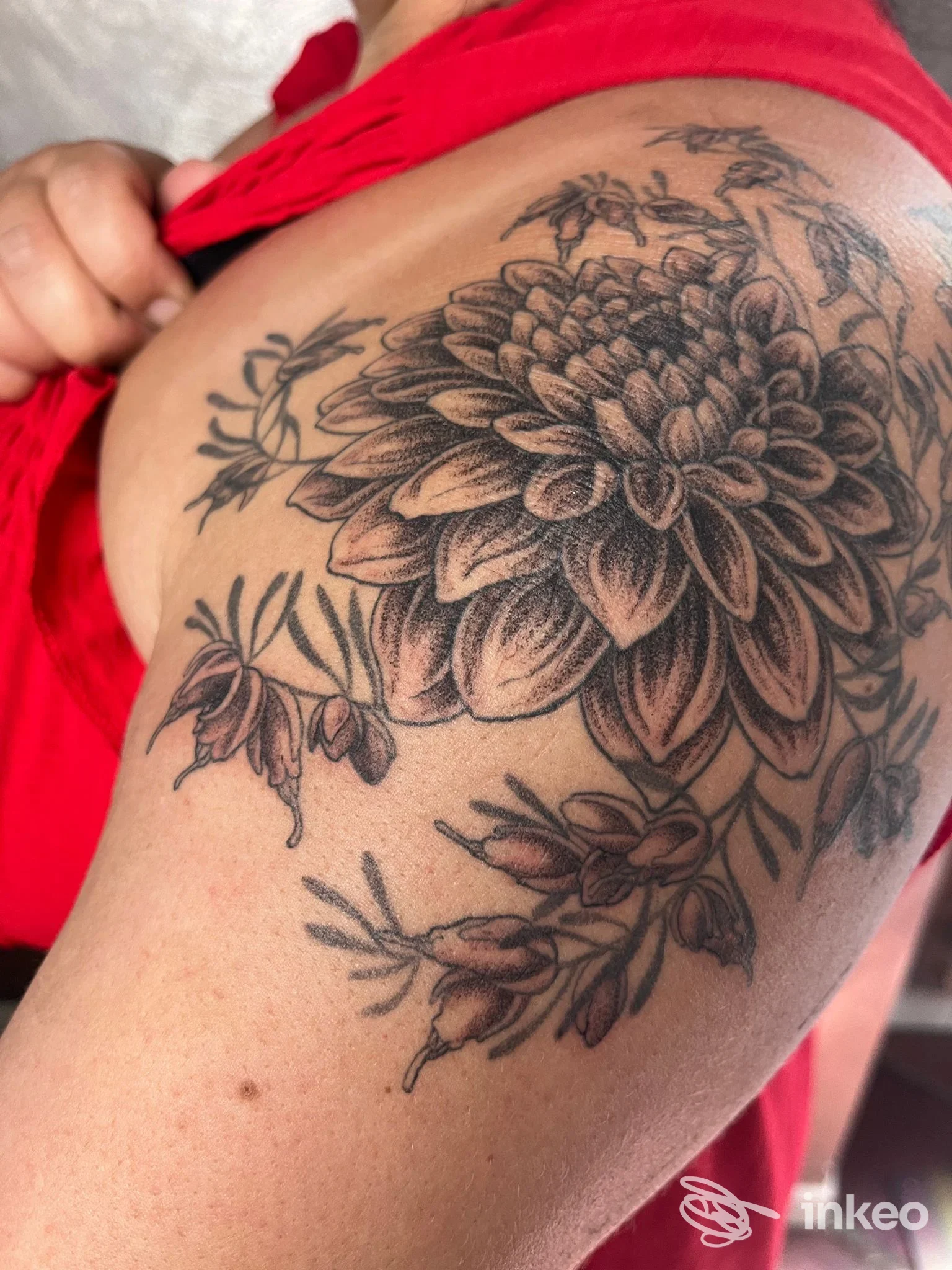 Tatuaggio floreale nero e grigio in primo piano sul deltoide/parte superiore del braccio, NeroPerla tattoo, Firenze.