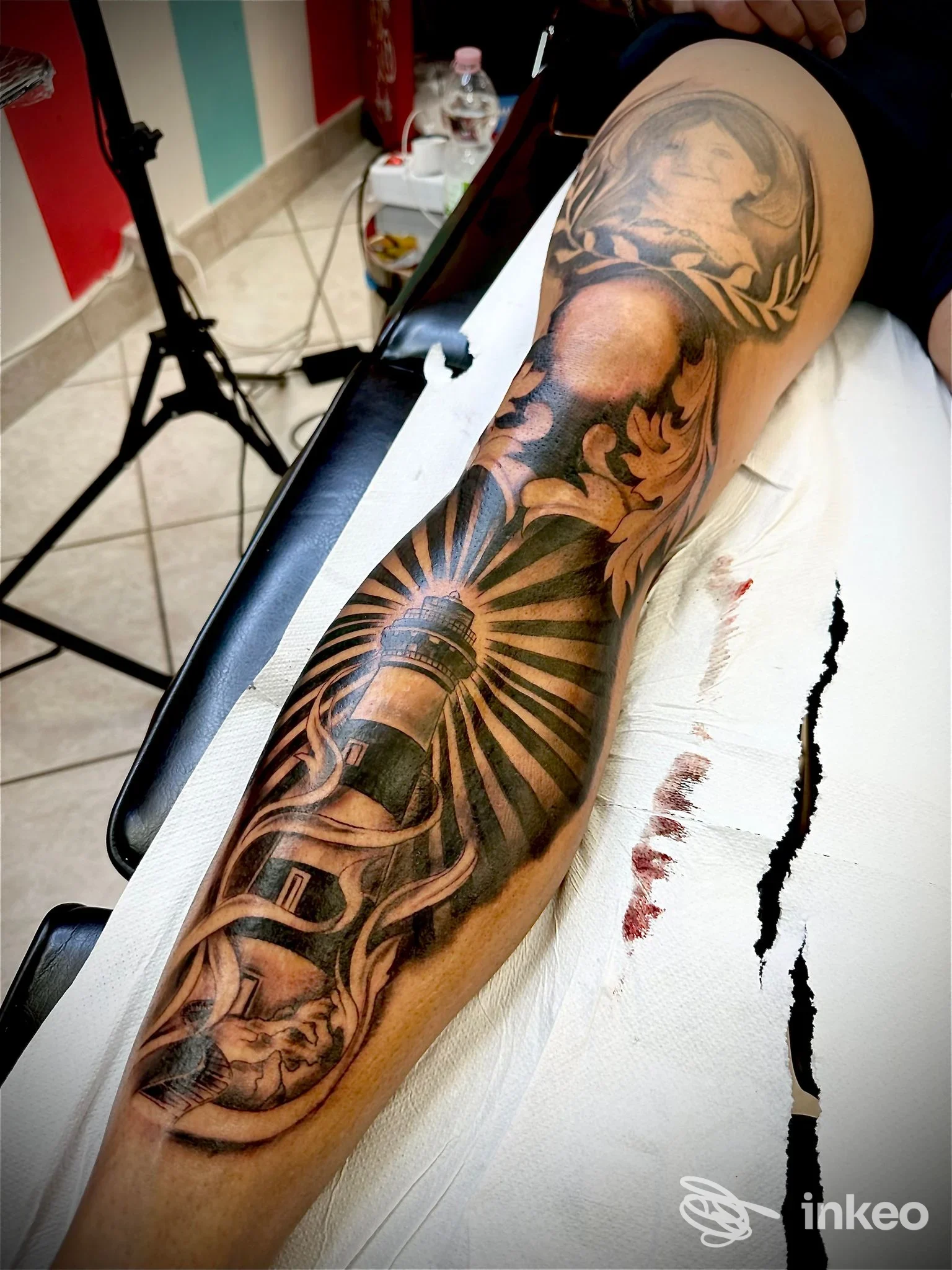 Mano e avambraccio tatuati con manica ornamentale e ritratti stilizzati, foto scattata in studio di tatuaggio.