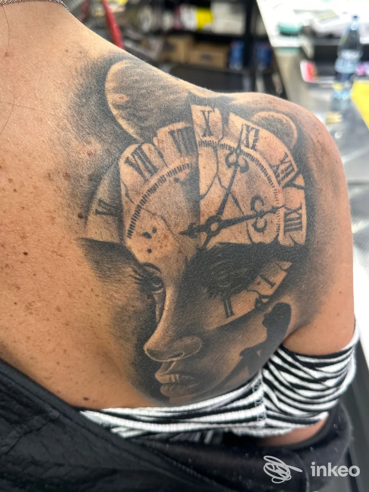 Grande tatuaggio in bianco e nero su spalla e parte superiore della schiena con volto stilizzato e quadrante d'orologio, Red & Black Tatoo Studio Arezzo.