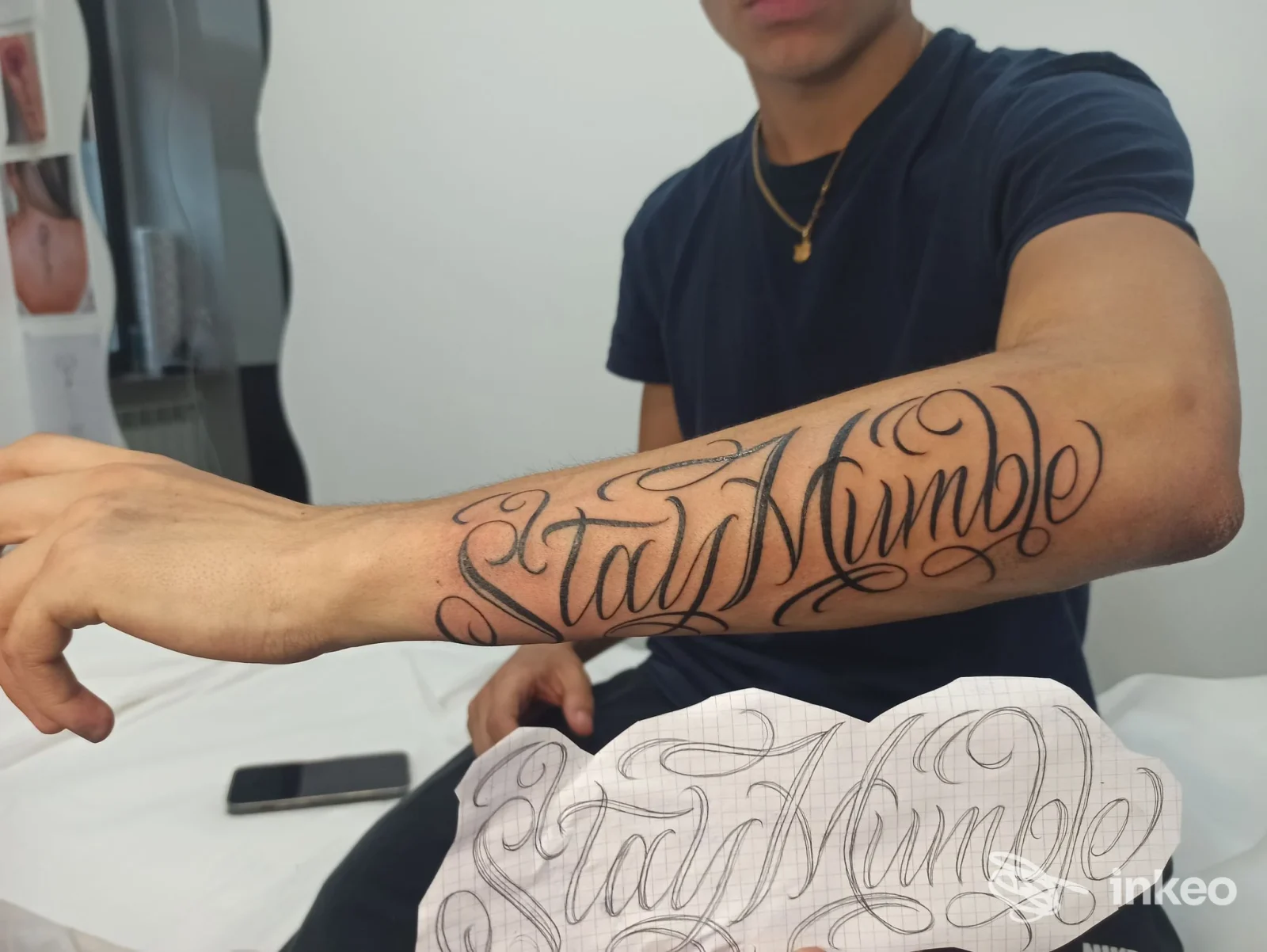 Braccio di un uomo con tatuaggio script lungo l’avambraccio destro: Stay Humble, stile decorativo, nello studio di tatuaggi Celtic Tattoo.
