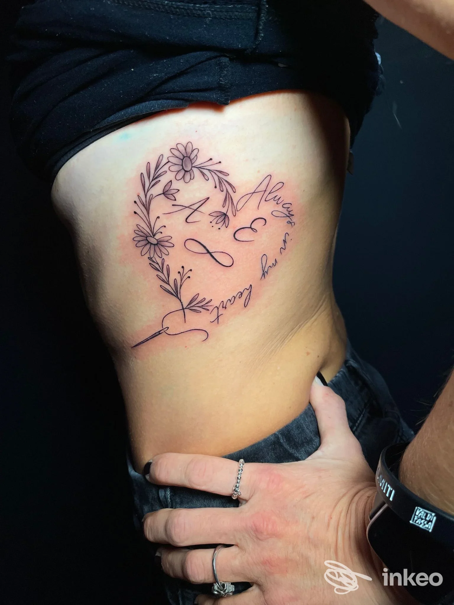 Tatuaggio a forma di cuore con fiori e scritte sul fianco, foto fornita da Sara D Tattoo Studio, Pontedera.